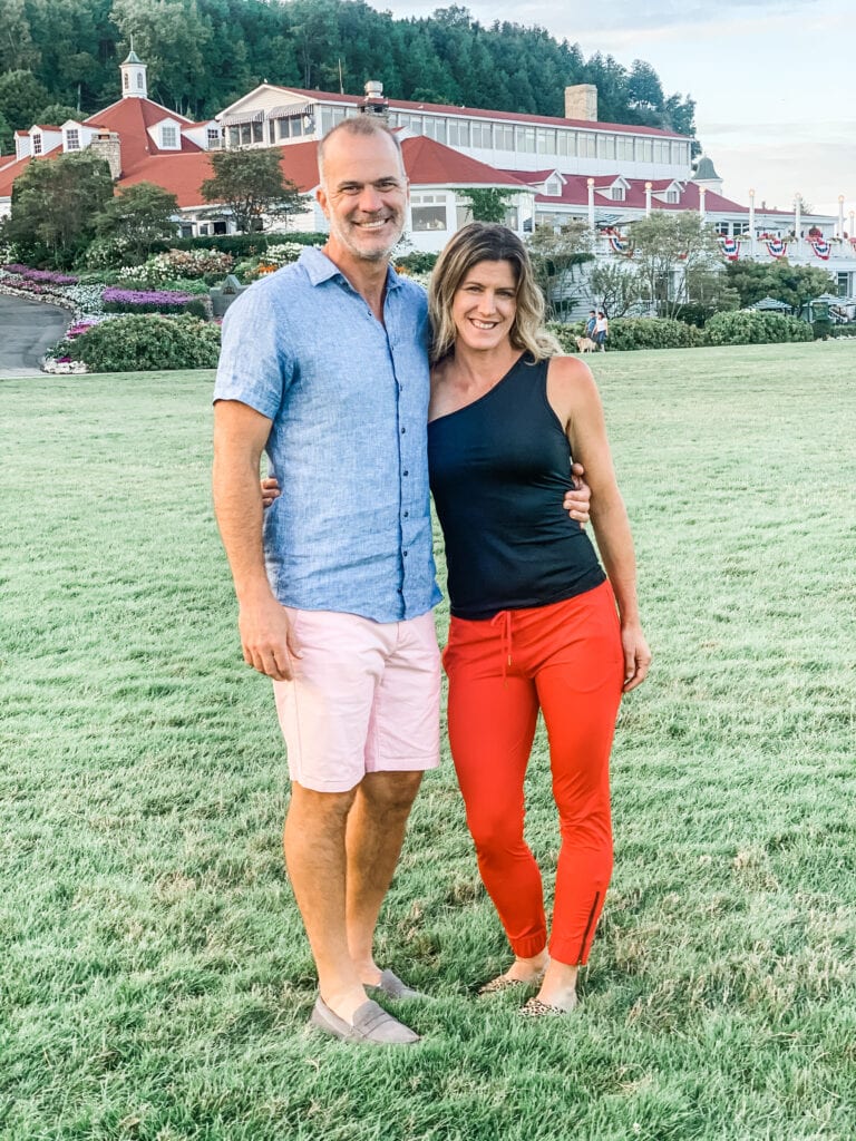 a couple standing in front of a large hotel on the lawn.