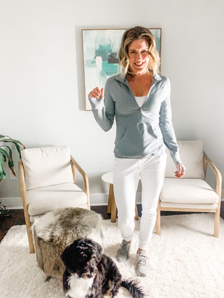 a woman in white joggers with a gray pullover and a dog