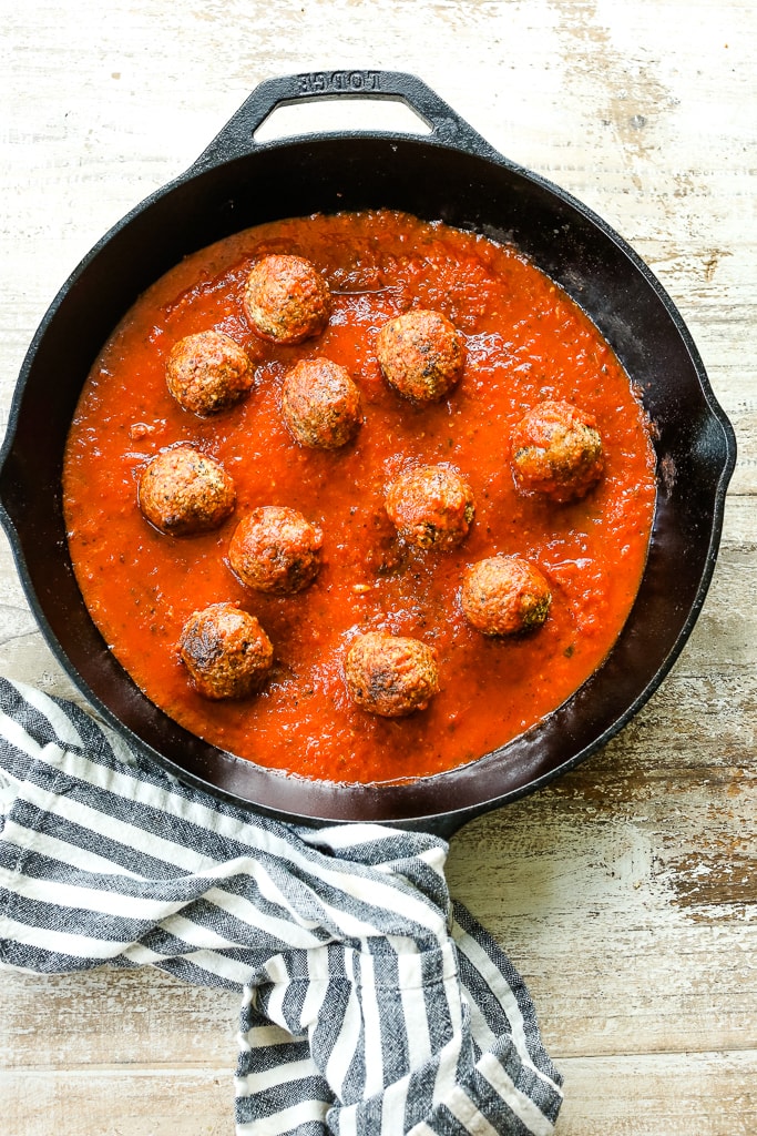 vegan meatballs in a cast iron skillet with spaghetti sauce