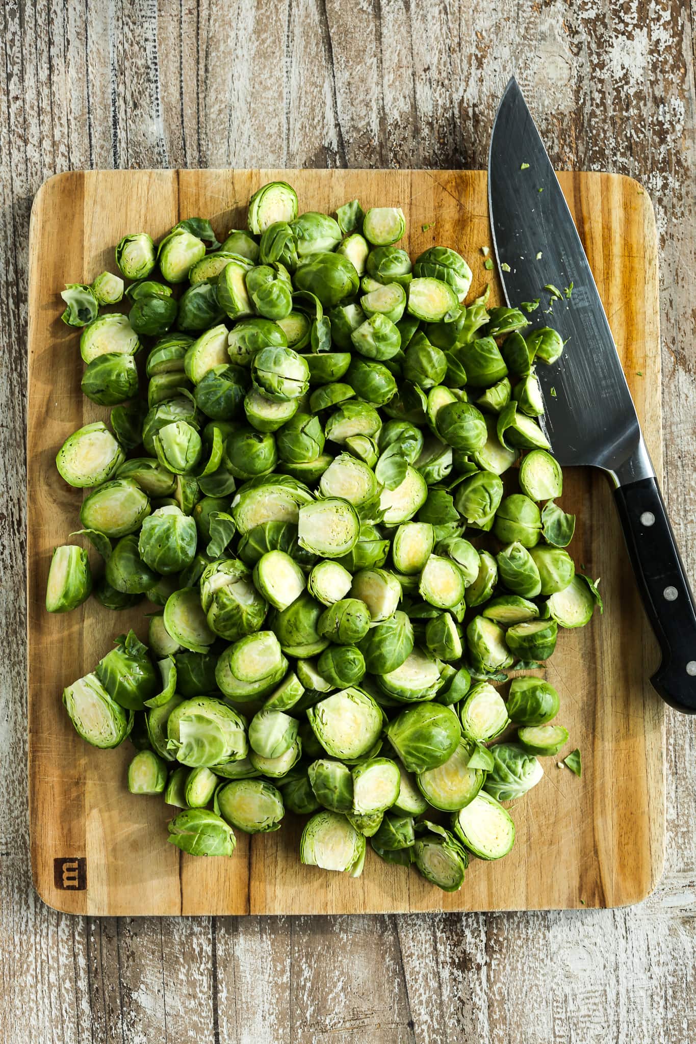 Brussels sprouts on a cutting board with knife, cut in half