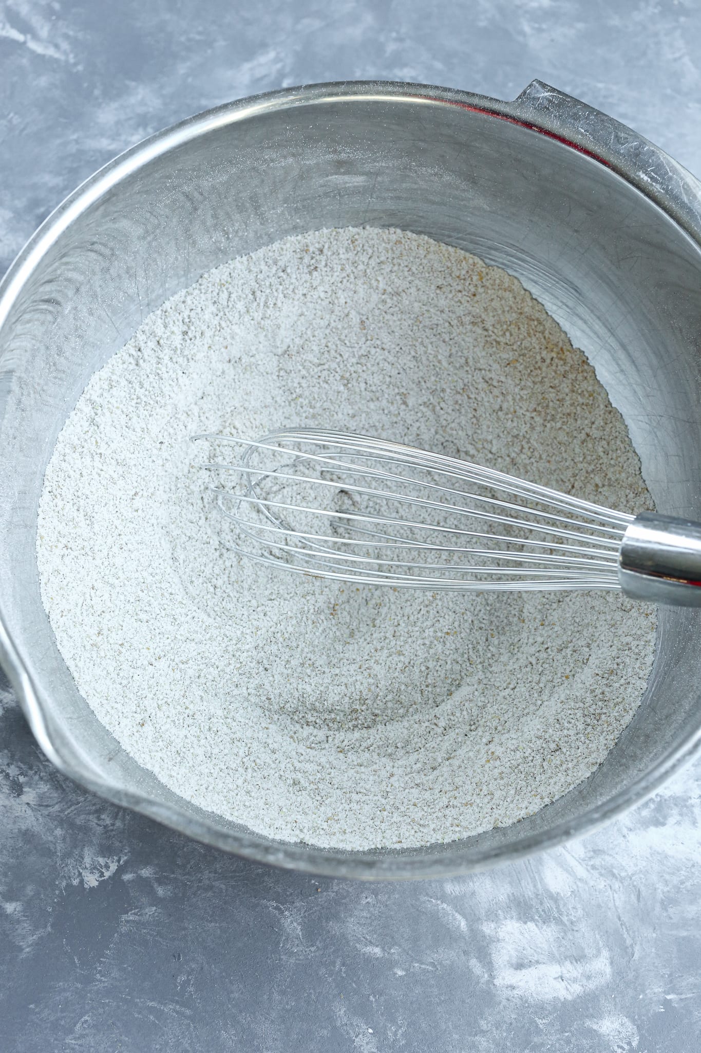 whisking flour in a large silver bowl