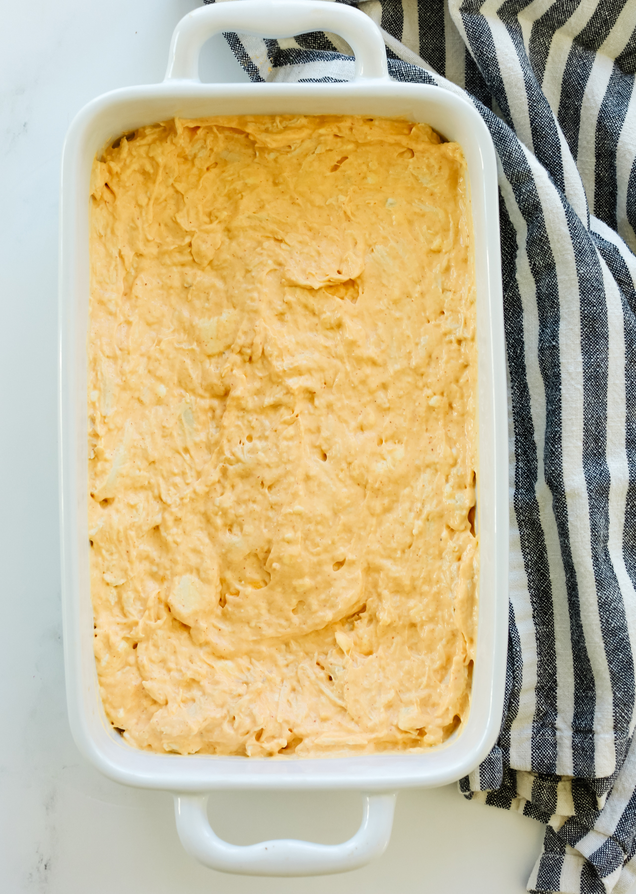 healthy buffalo chicken dip in a white baking dish before being baked