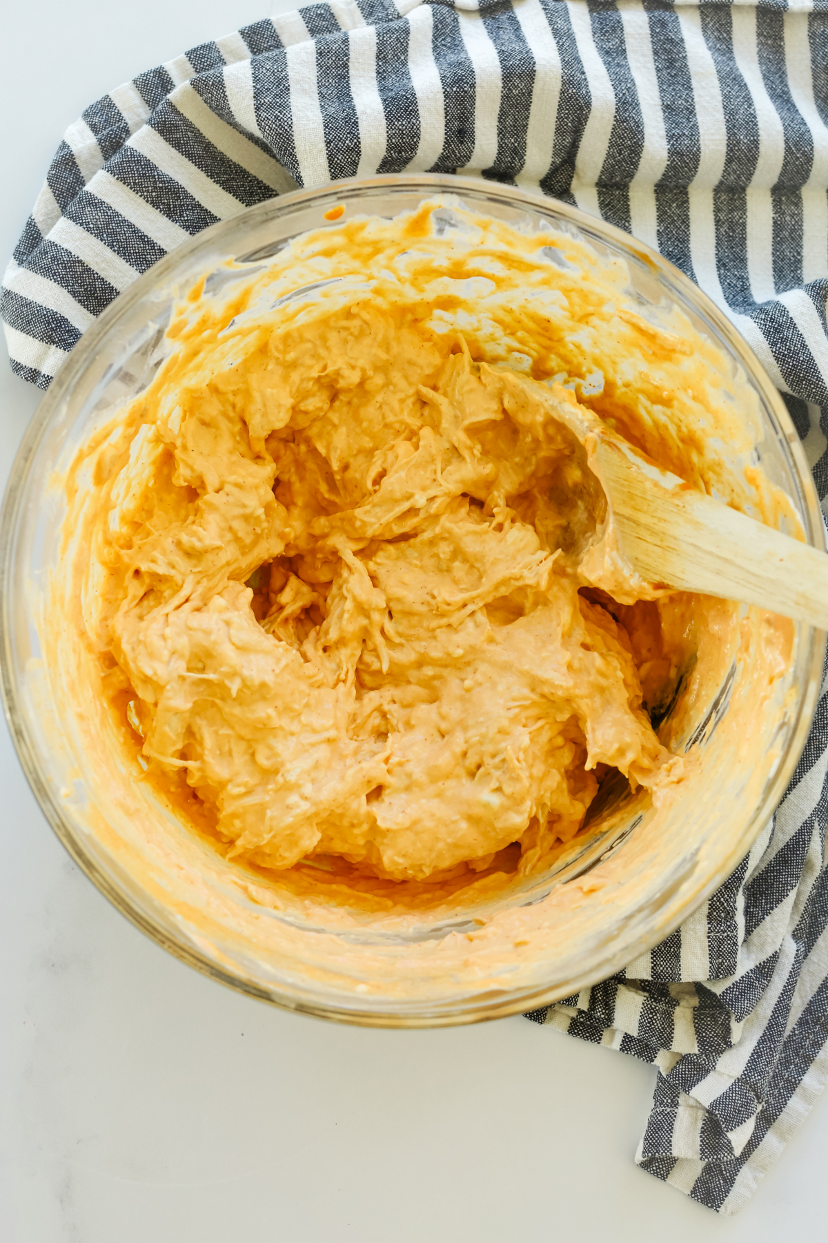 stirring ingredients together in a glass bowl with a wooden spoon