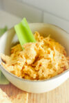 a bowl of healthy buffalo chicken dip with a celery stalk sticking out