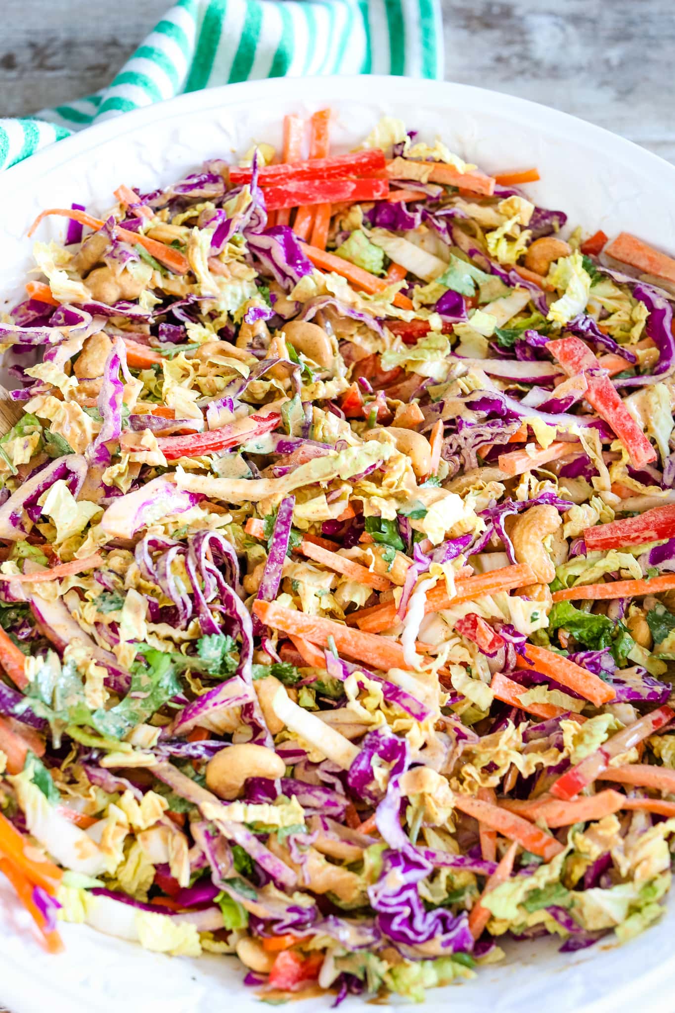 an overhead shot of salad in a white bowl with dressing mixed in