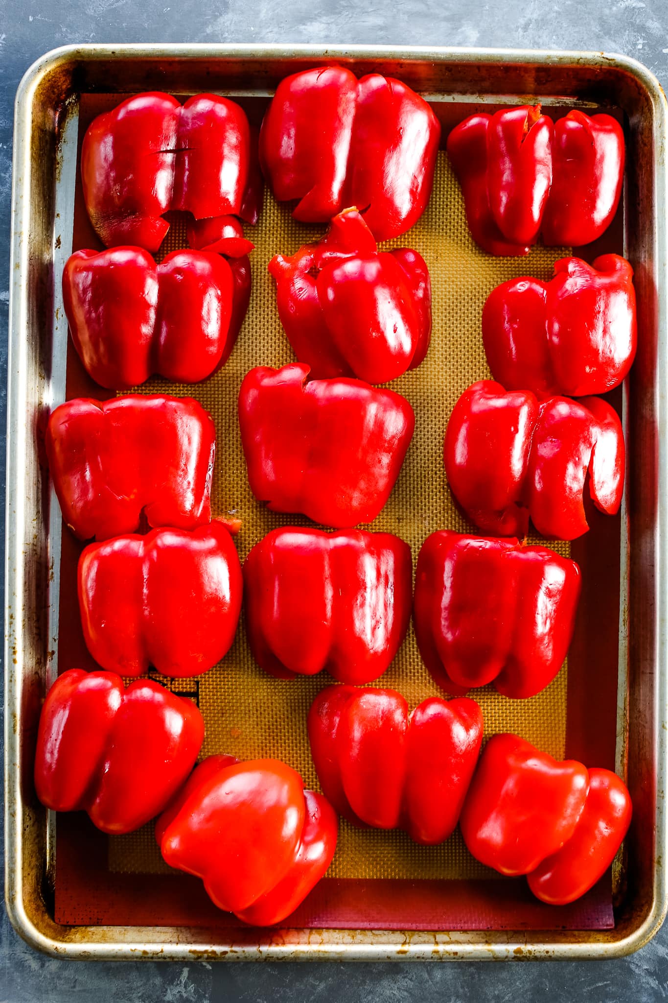 how to roast red peppers in the oven--step 1 raw peppers on a sheet pan
