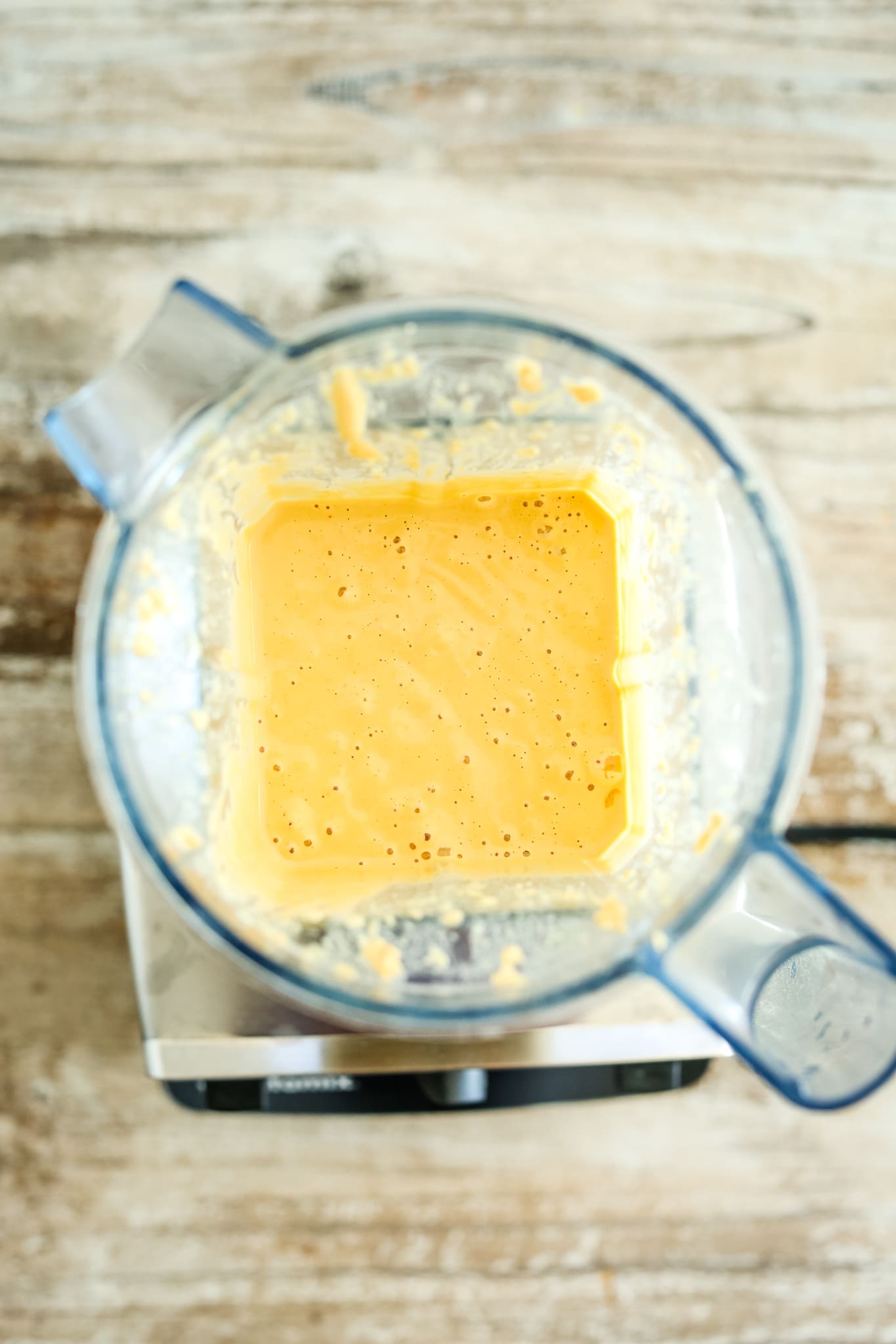 an overhead shot looking into the top of a blender with an orange liquid inside