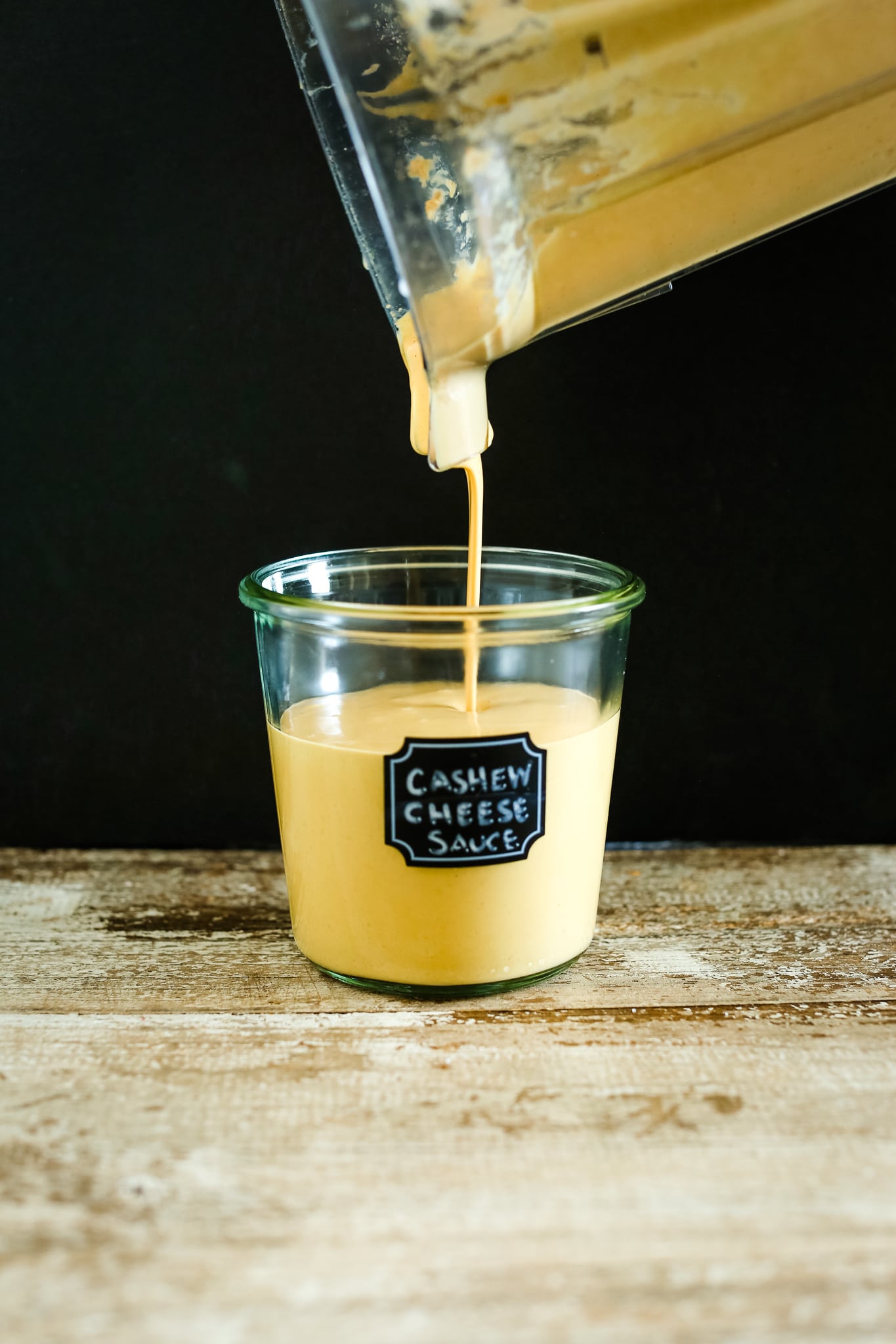 pouring cashew cheese sauce from the blender into a jar