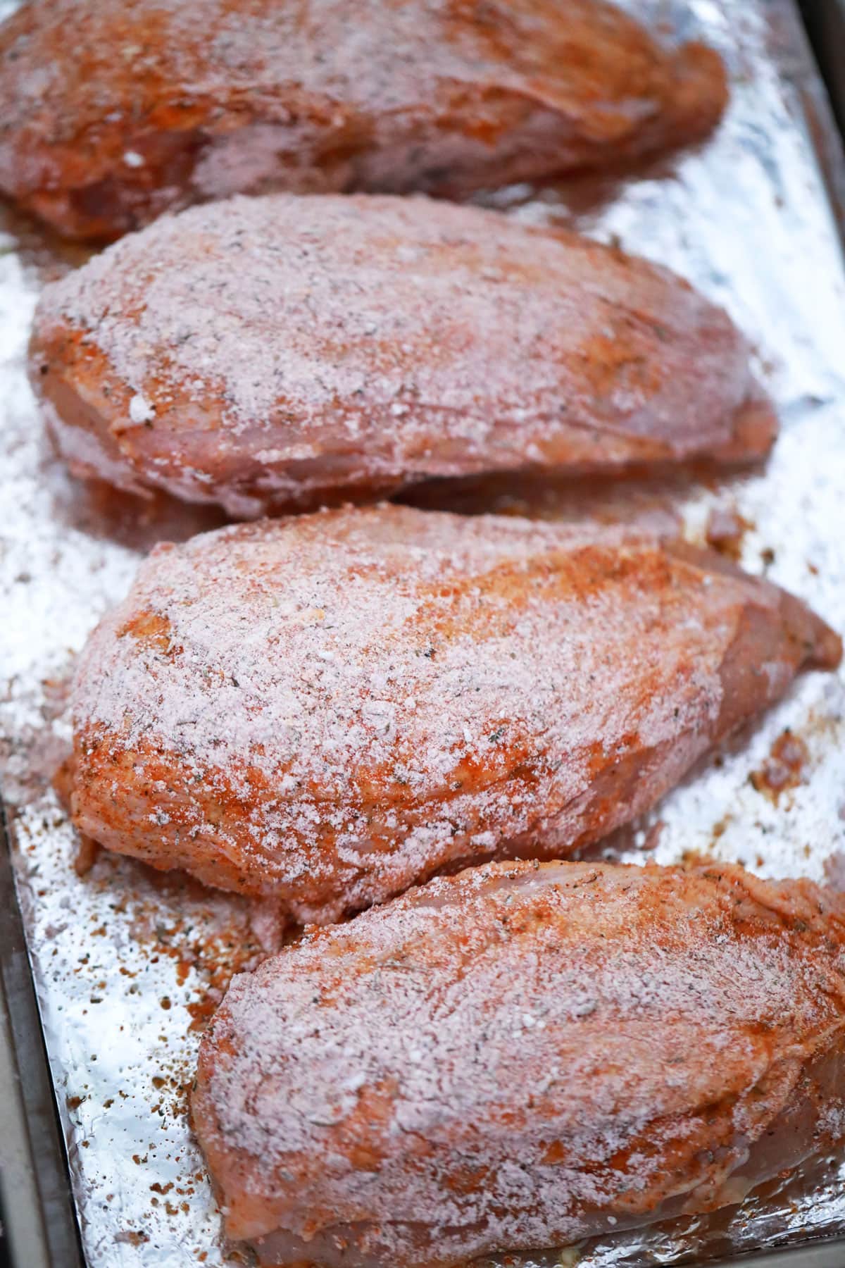 prepping baked bone in chicken breasts with seasoning
