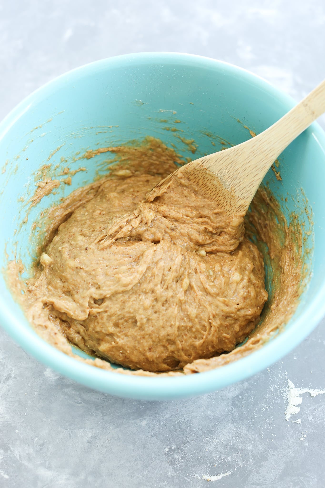 stirring the batter with a wooden spoon in a turquoise bowl