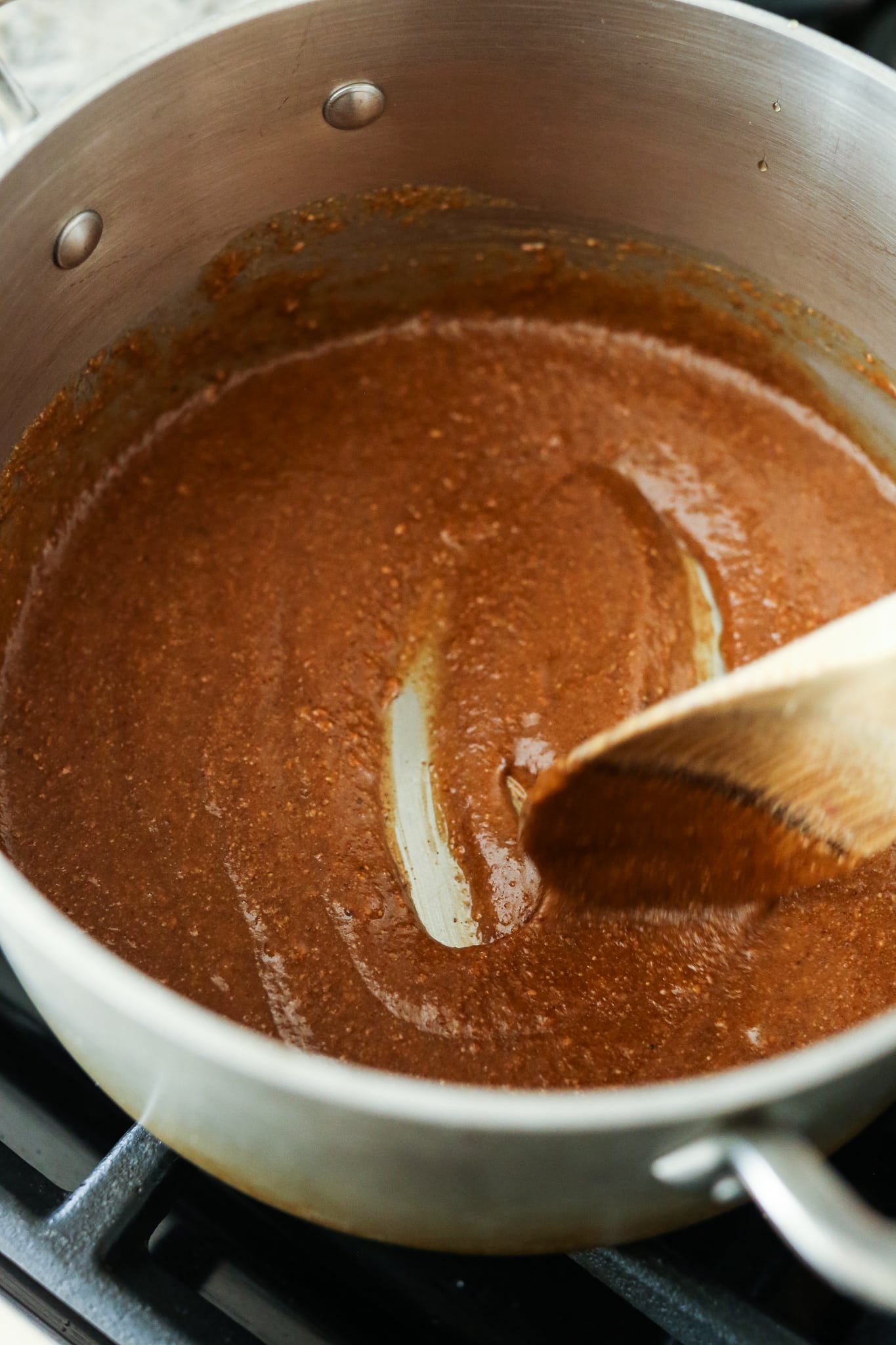 combining almond butter and maple syrup in a sauce pan with a wooden spoon