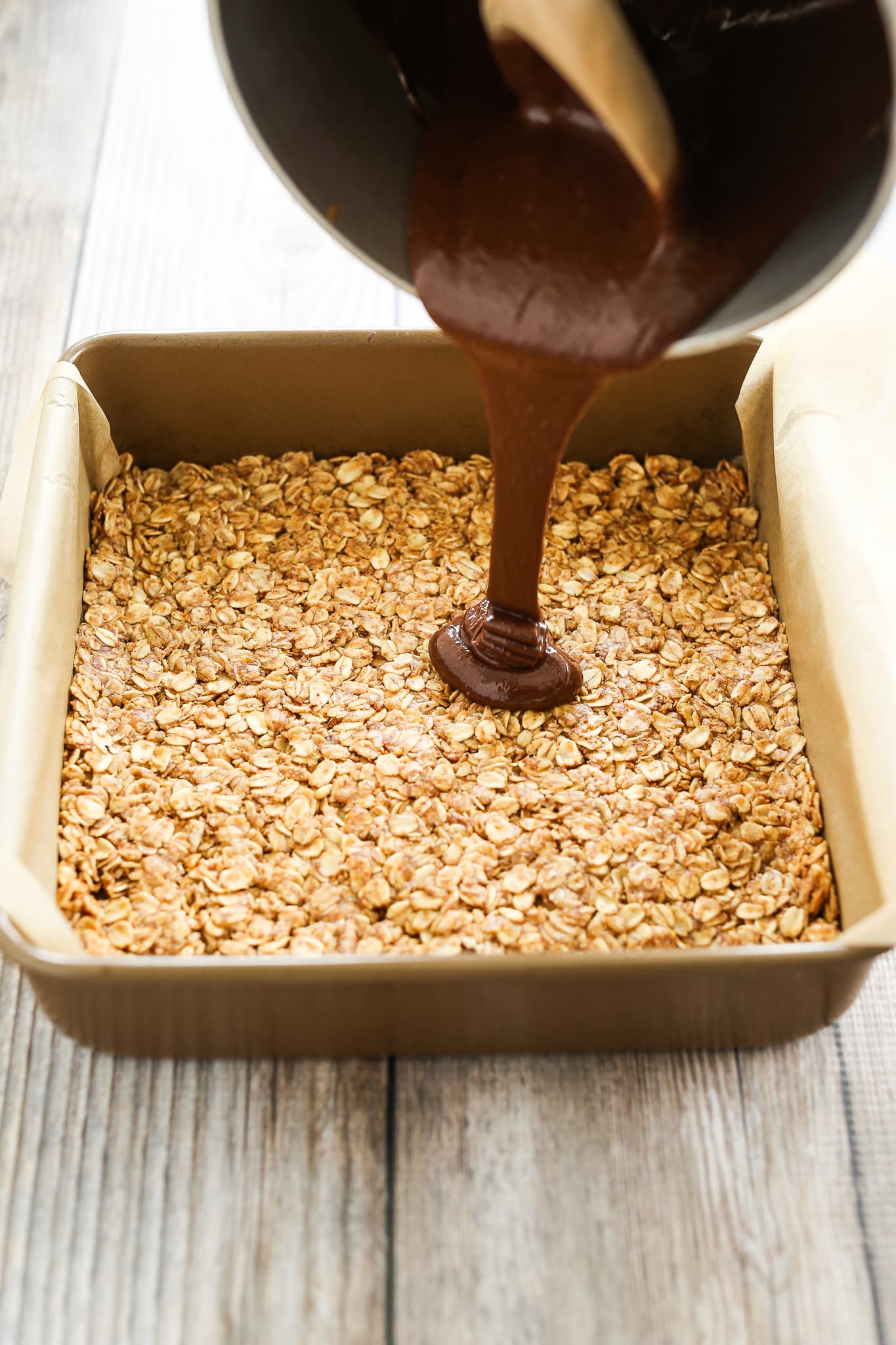 pouring chocolate mixture onto layer bars