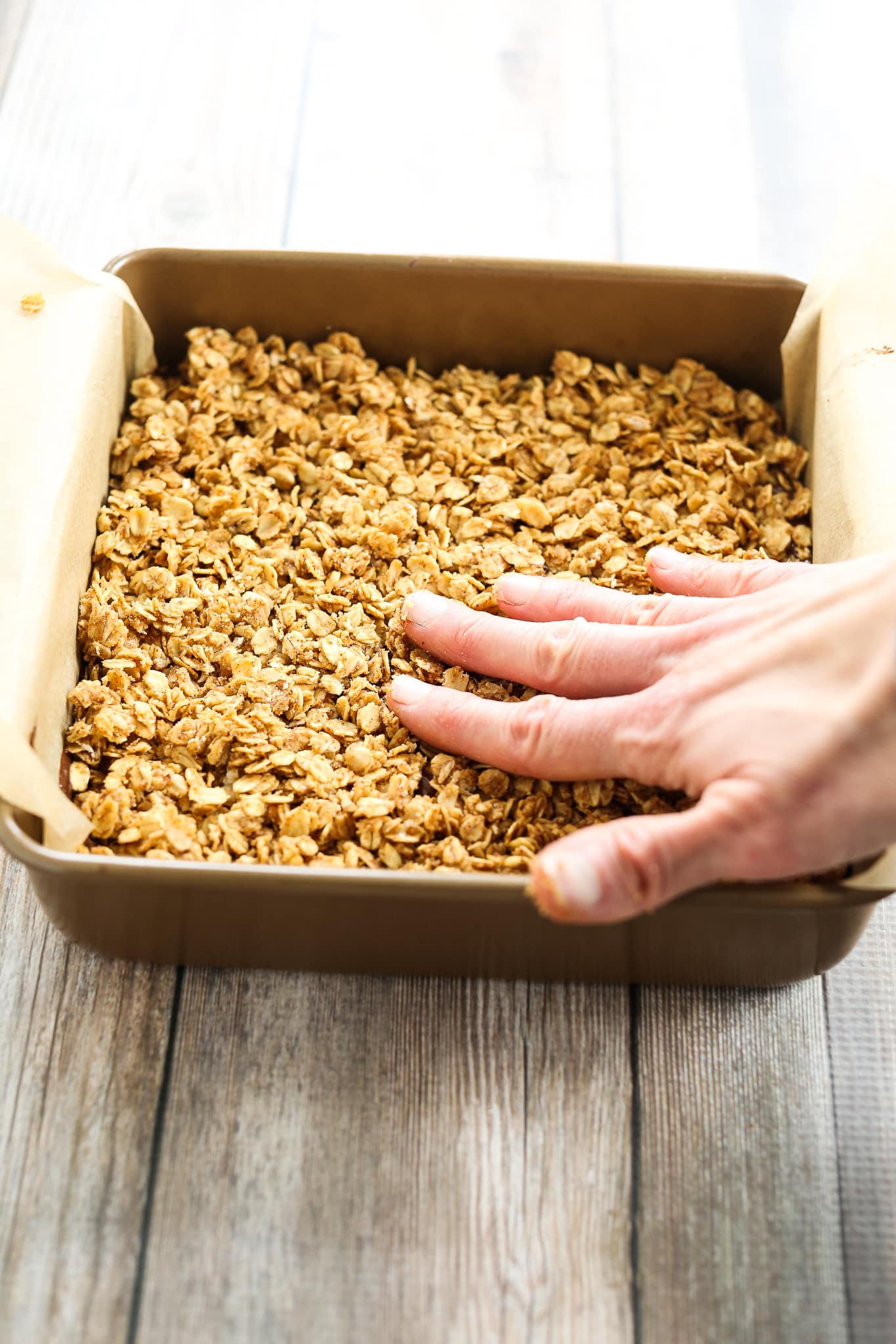 pressing oat mixture down with hands