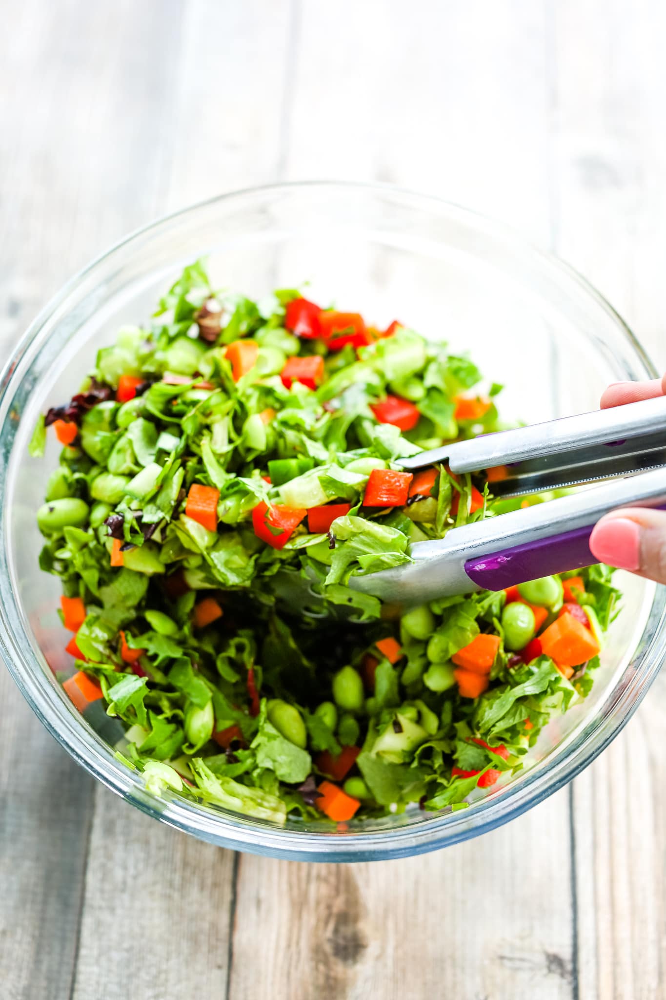 mixing salad ingredients together with tongs