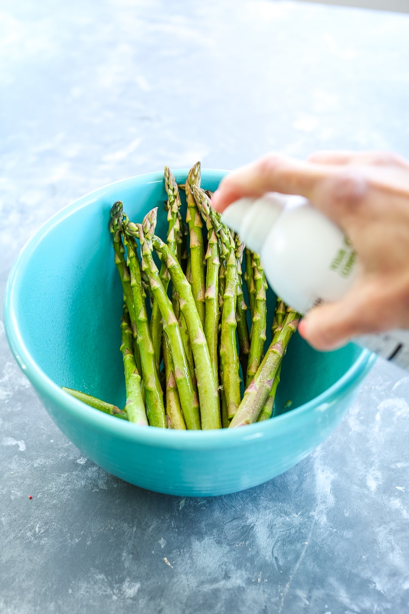 spraying asparagus with cooking oil