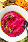 Beetroot hummus with carrots crackers and cucumbers on a board