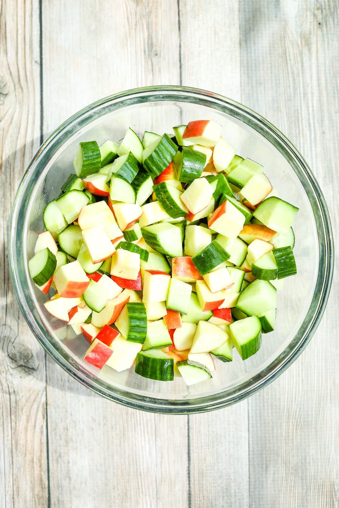 chopped apples and chopped cucumbers in a glass bowl