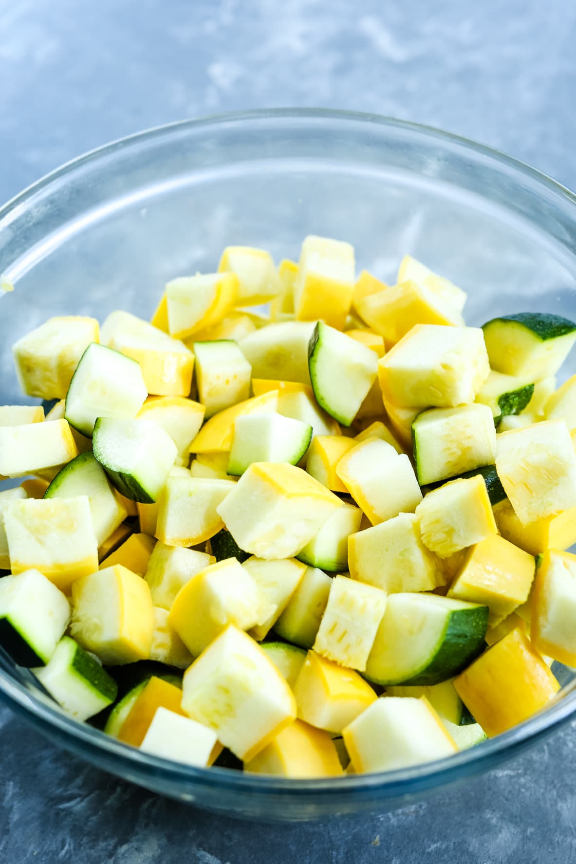 zucchini and squash cut into triangle shapes pieces in a clear glass bowl