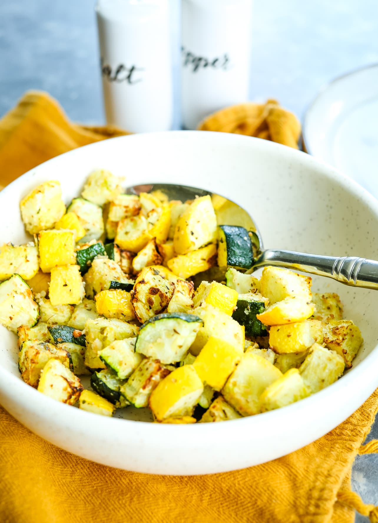 scooping out zucchini and squash from a white bowl