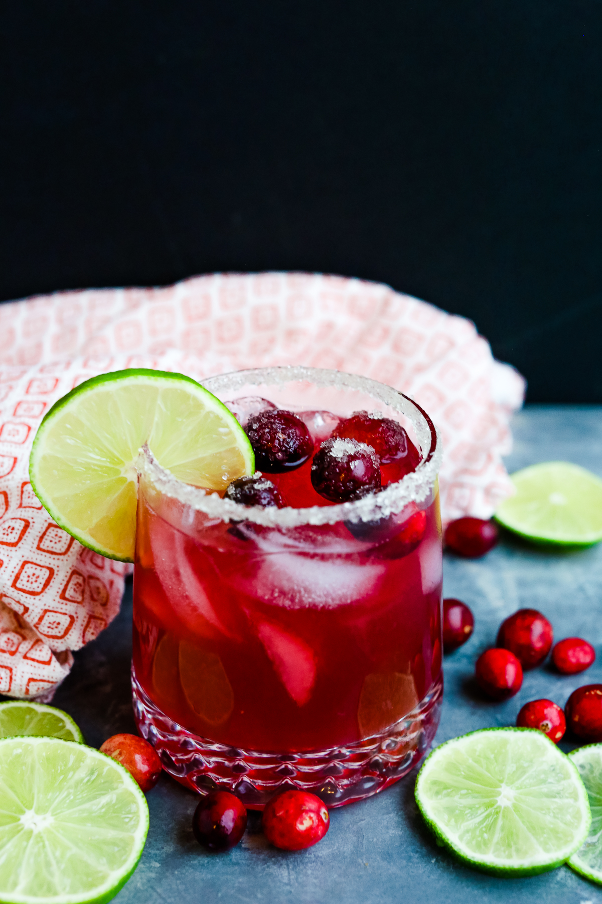 cranberry margarita with a sugar rim, lime wheel, and fresh cranberries