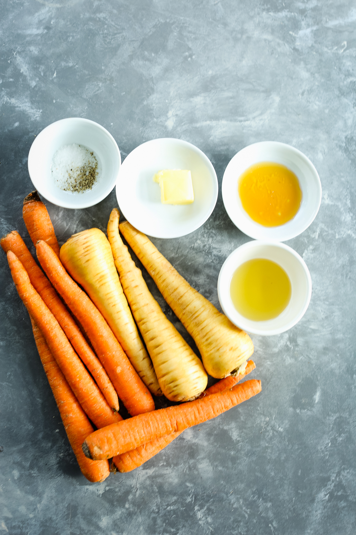 honey roasted carrots and parsnips recipe ingredients on a gray board