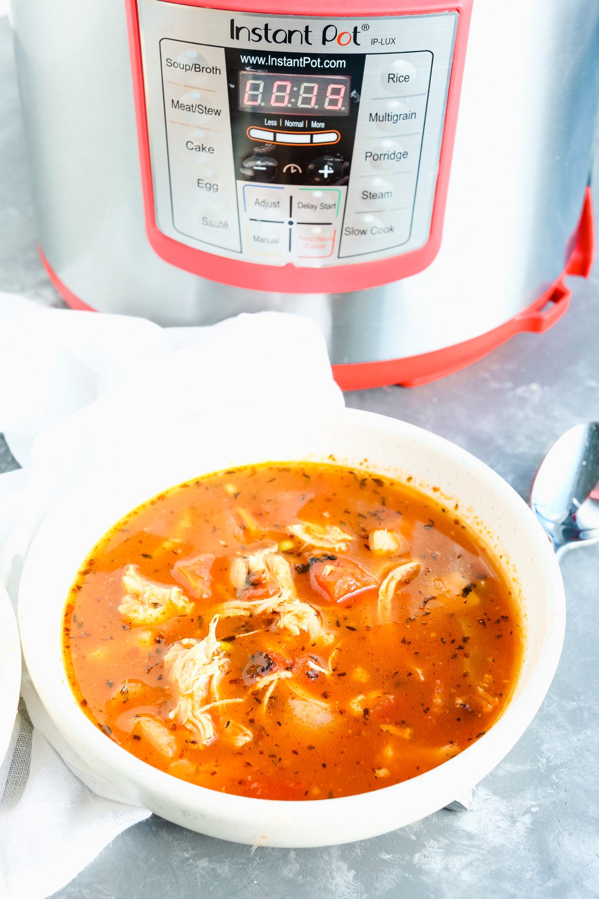 Instant Pot chicken vegetable soup recipe in a bowl with instant pot in the background
