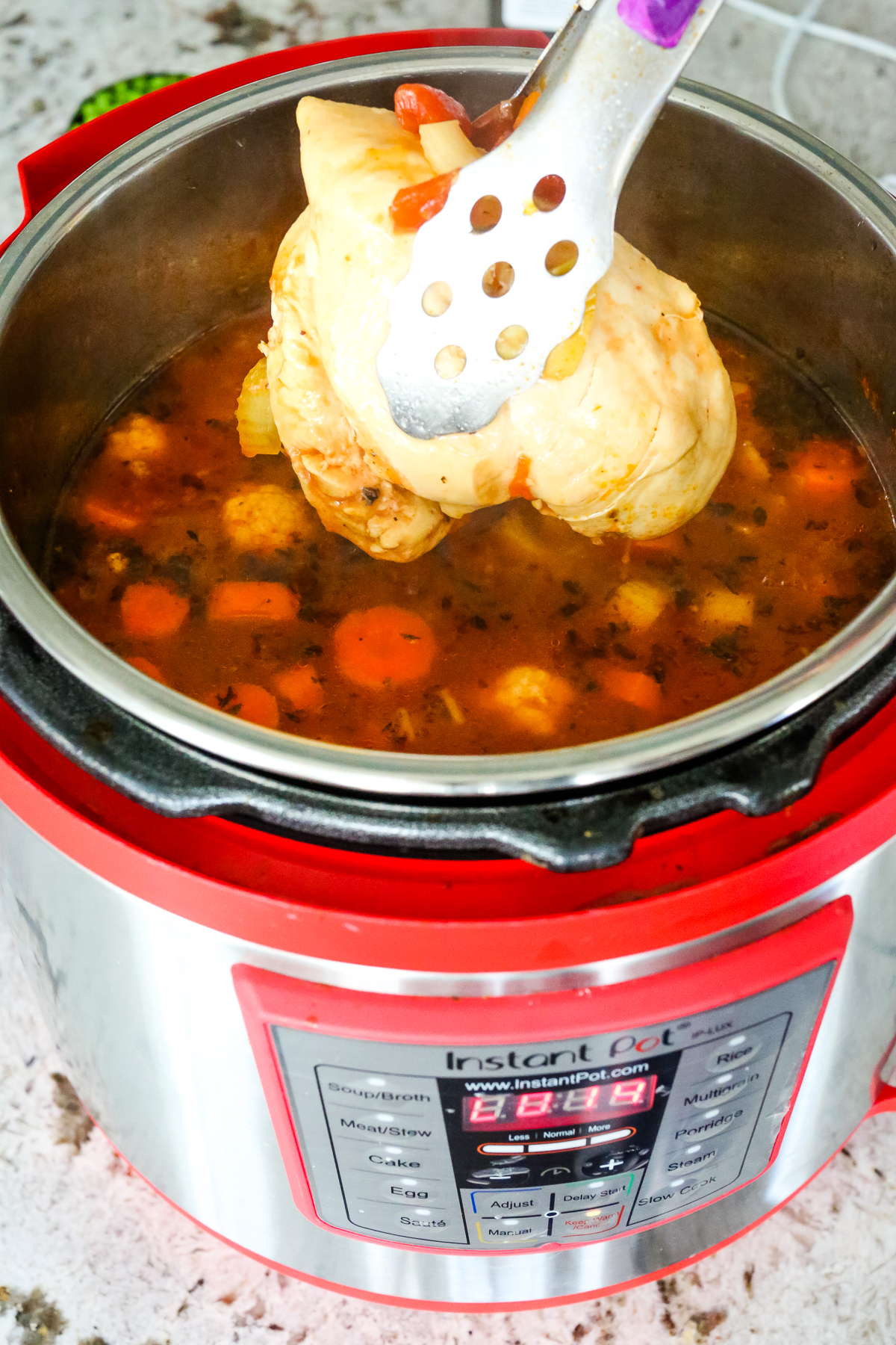 tongs pulling chicken out of the soup