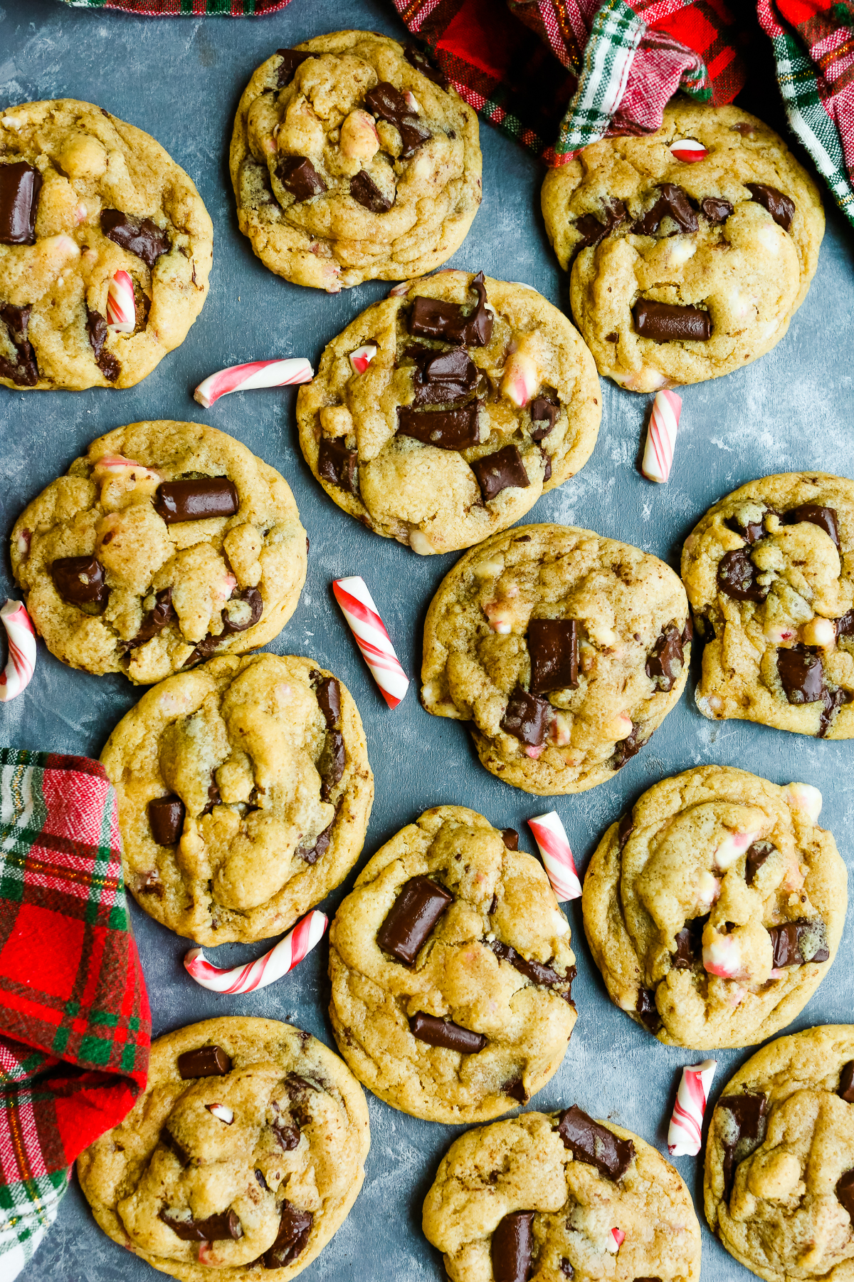 an overhead shot of cookies on a table with chocolate chunks and candy cane pieces