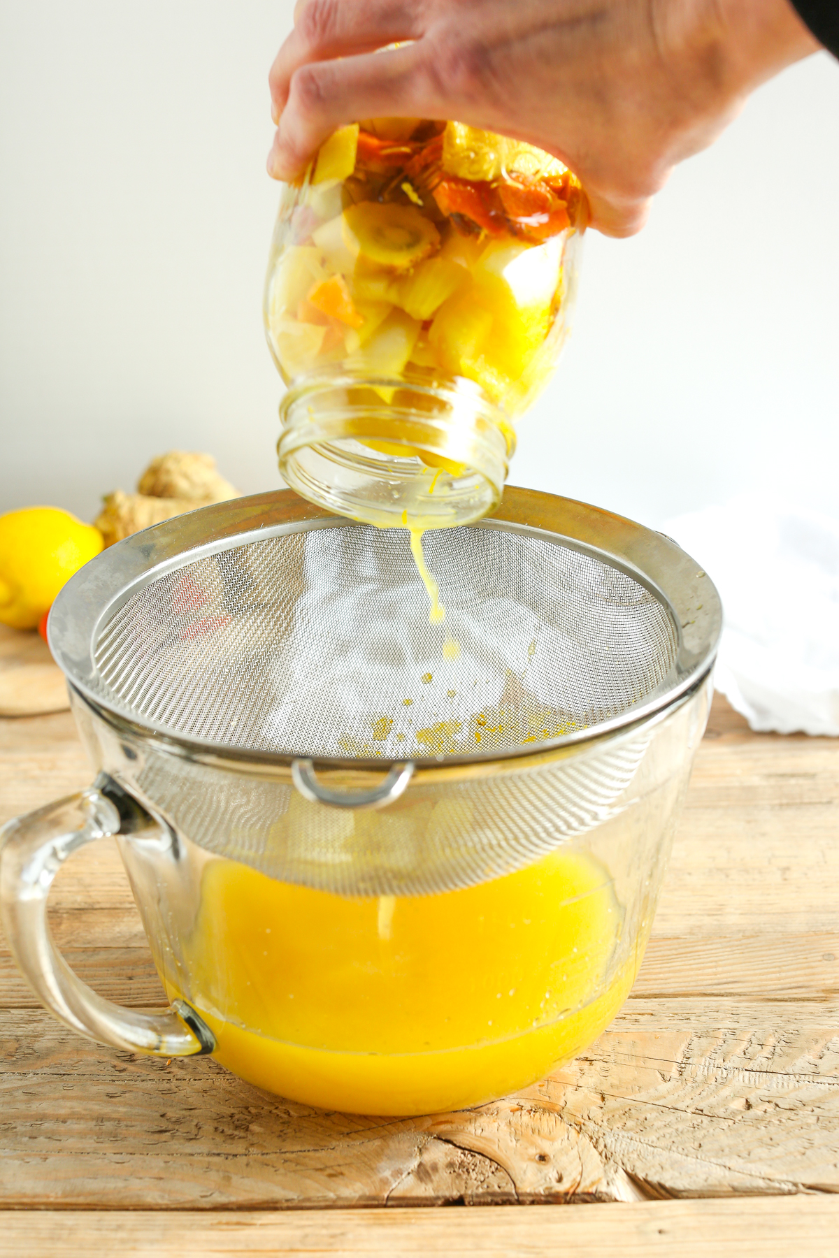straining fire cider through a fine mesh sieve 