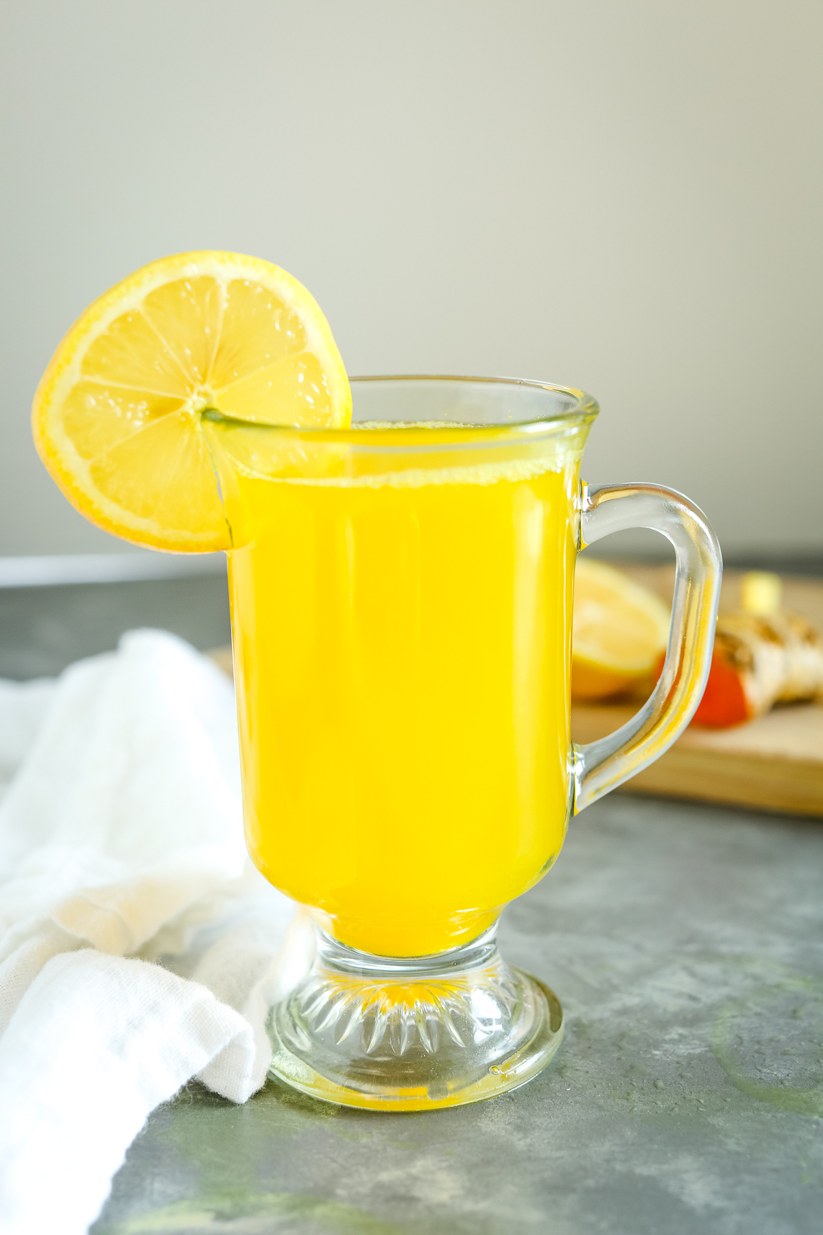 Lemon Ginger Turmeric Tea in a clear mug with a lemon wheel on the rim