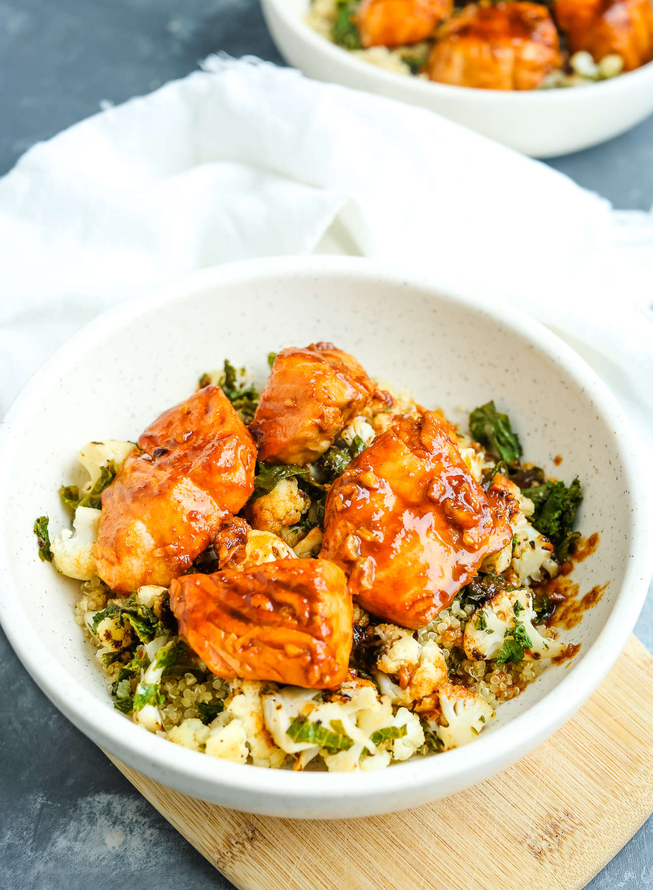 Salmon quinoa bowl in a white bowl on a wood board