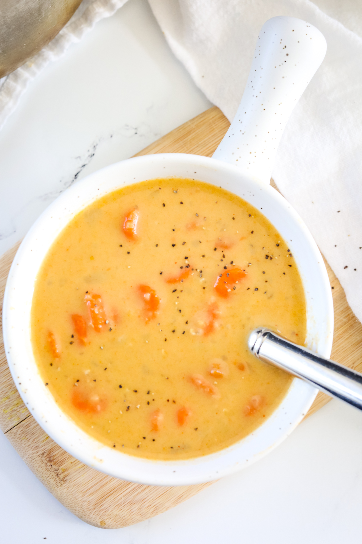 Carrot and Lentil Soup recipe with pepper and a spoon in a white bowl--overhead shot