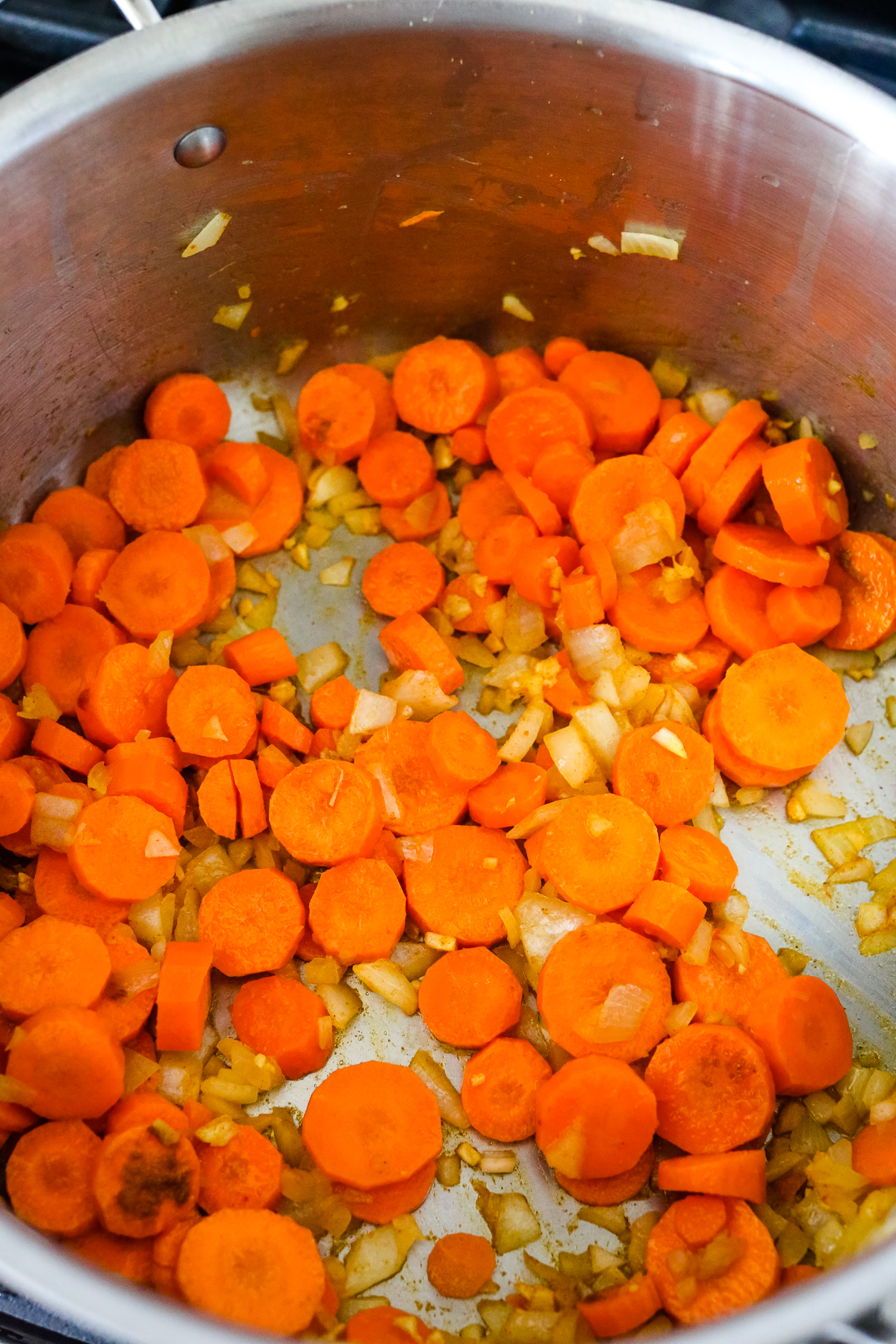 carrots and onions sauteing in a pot