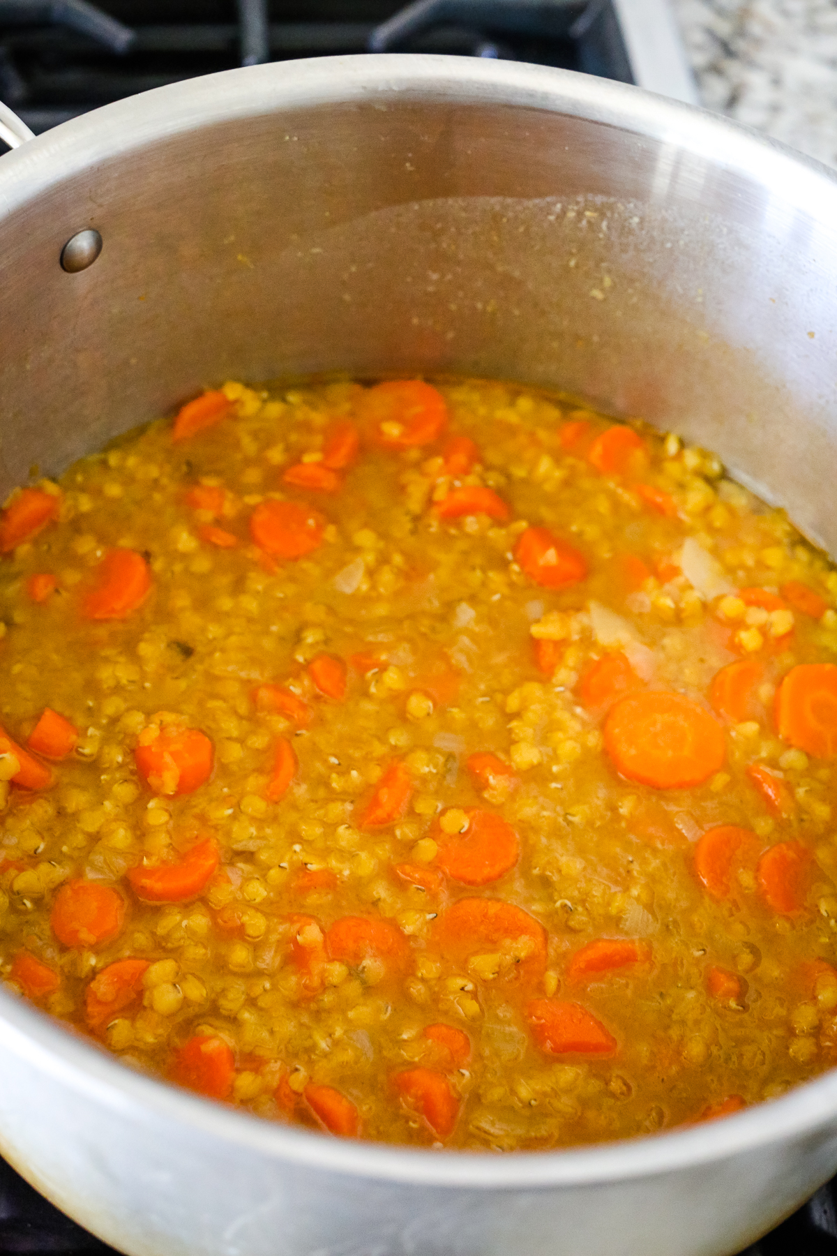 lentils and carrots in broth in a big soup pot