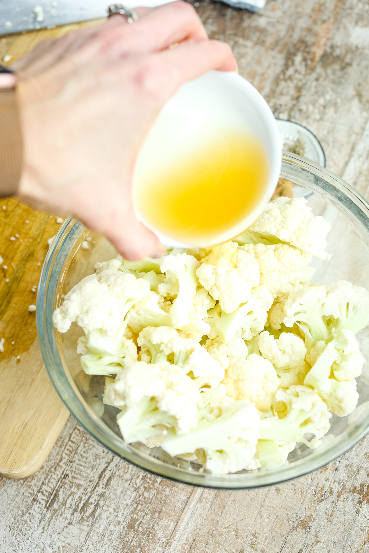 pouring oil over a bowl of cauliflower