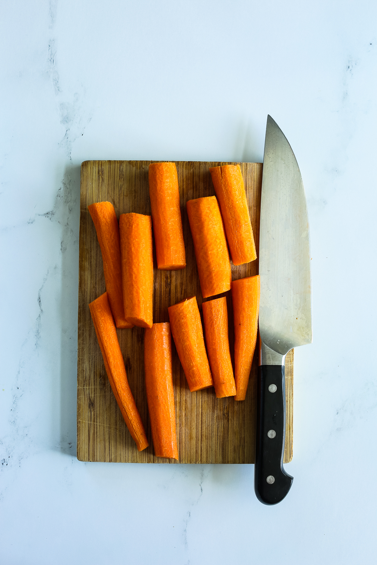 carrots cut in half on a cutting board with a knife