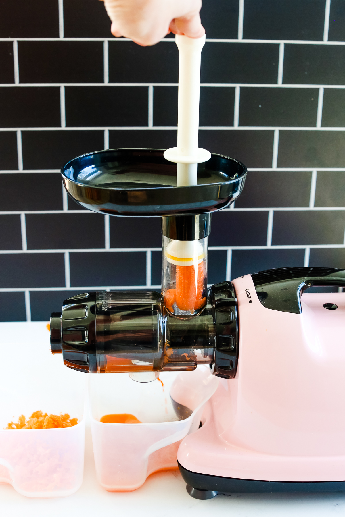 pushing carrots into the top of a pink juicer