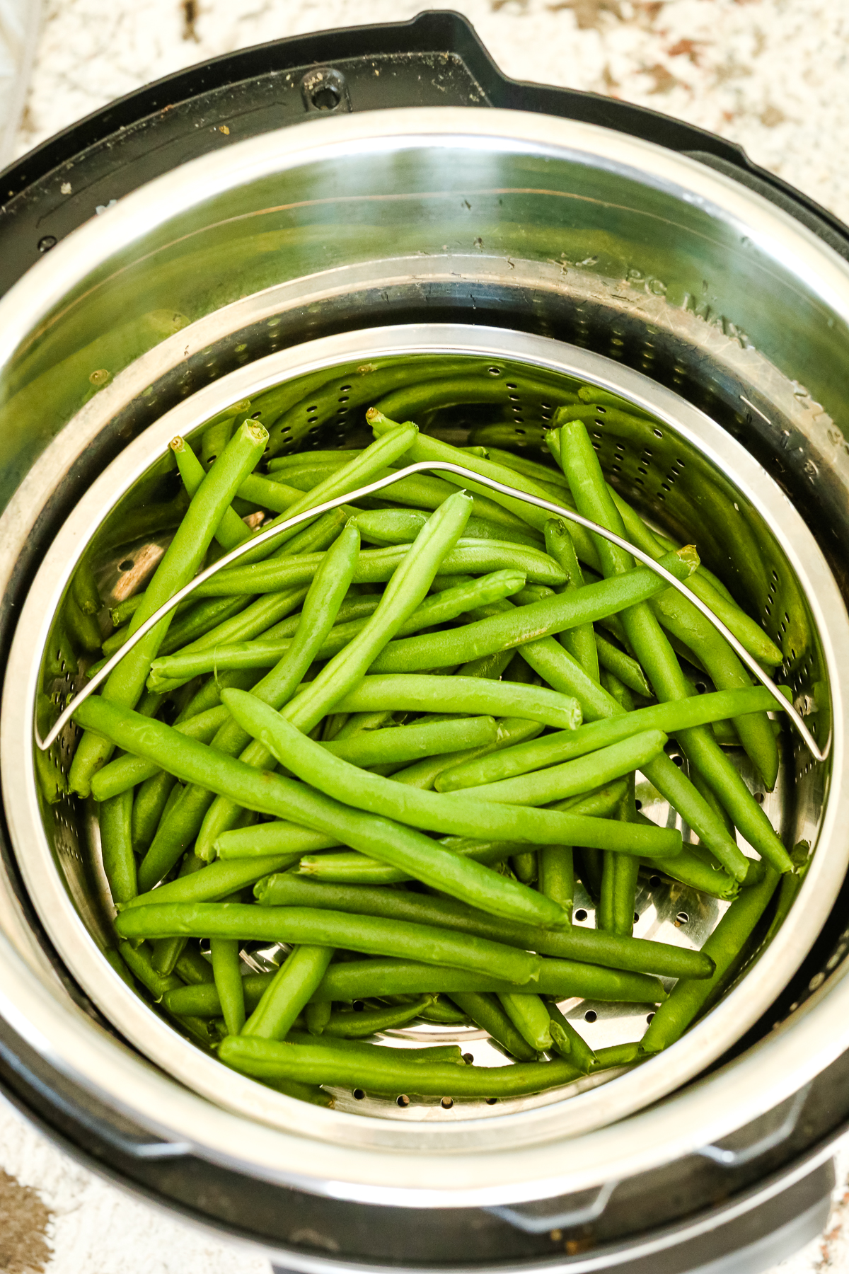 green beans in a steamer basket inside the inner pot of an Instant Pot pressure cooker