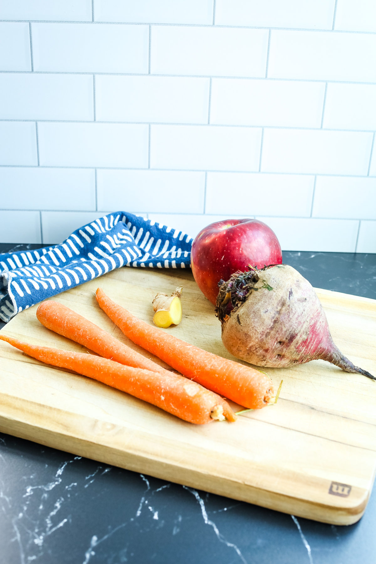 recipe ingredients for ABC Juice on a board: carrots, beetroot, a whole apple, and a piece of ginger root