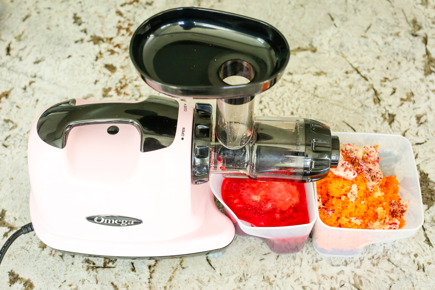 a pink juicer with pulp and a vibrant red juice