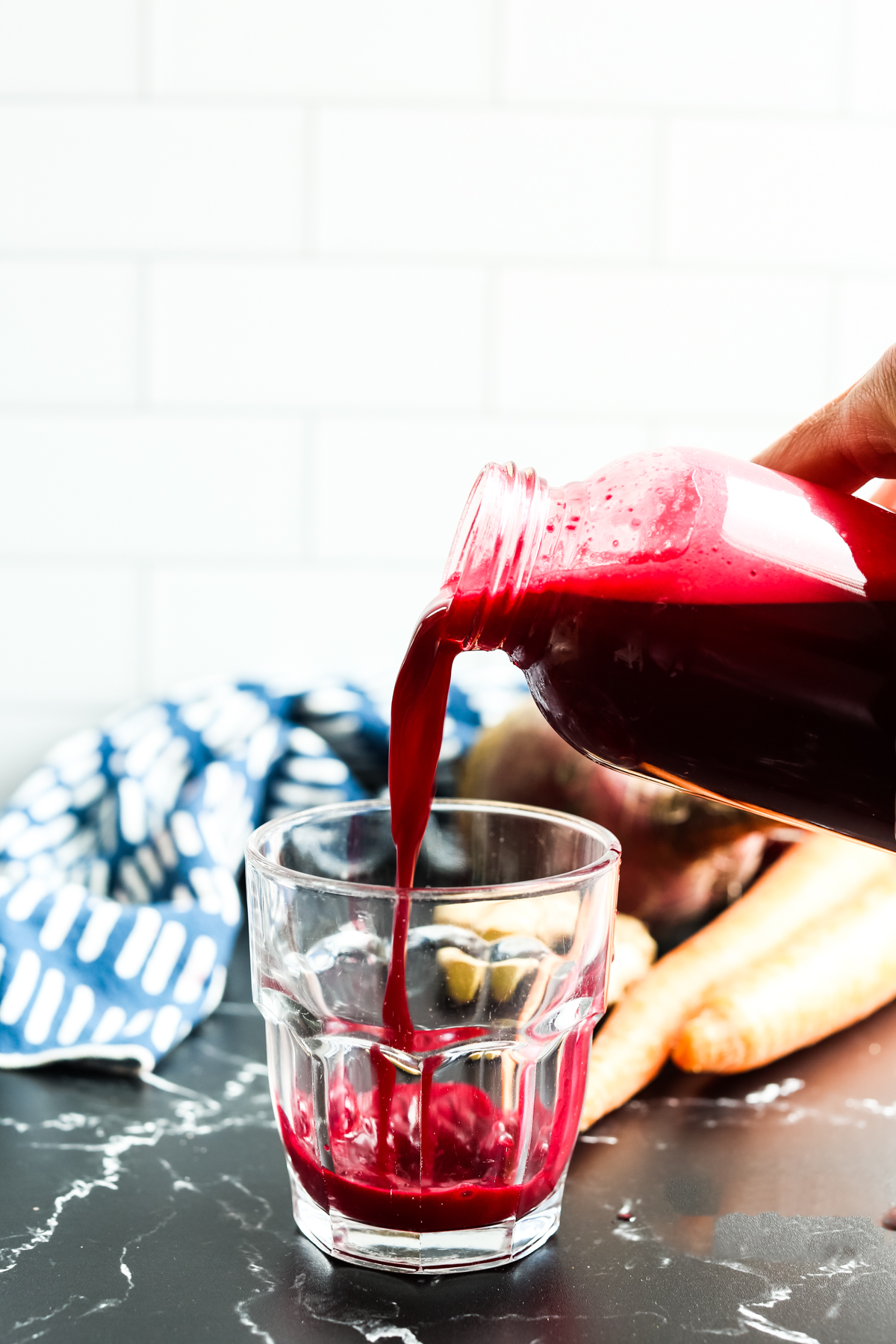 pouring a vibrant deep red drink into a glass