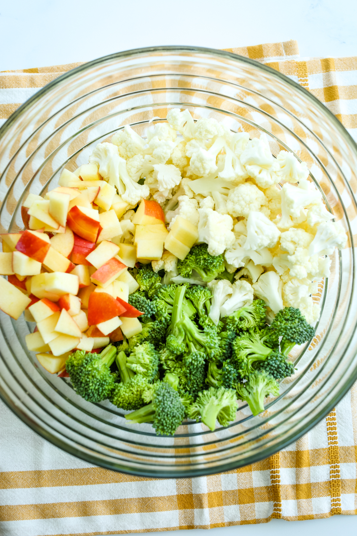 broccoli, cauliflower, and apple in a glass bowl