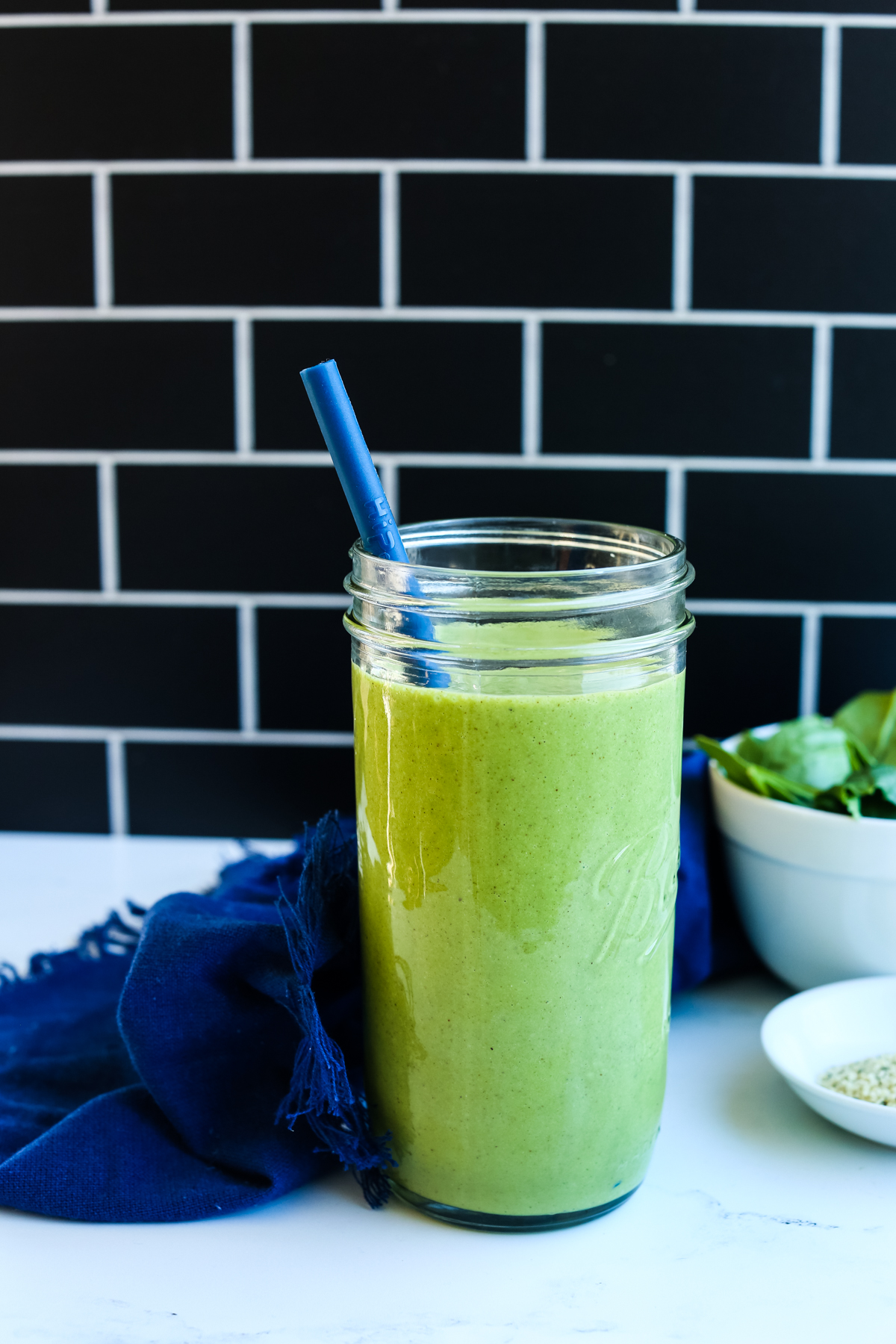 Green power smoothie in a ball mason jar with a blue straw