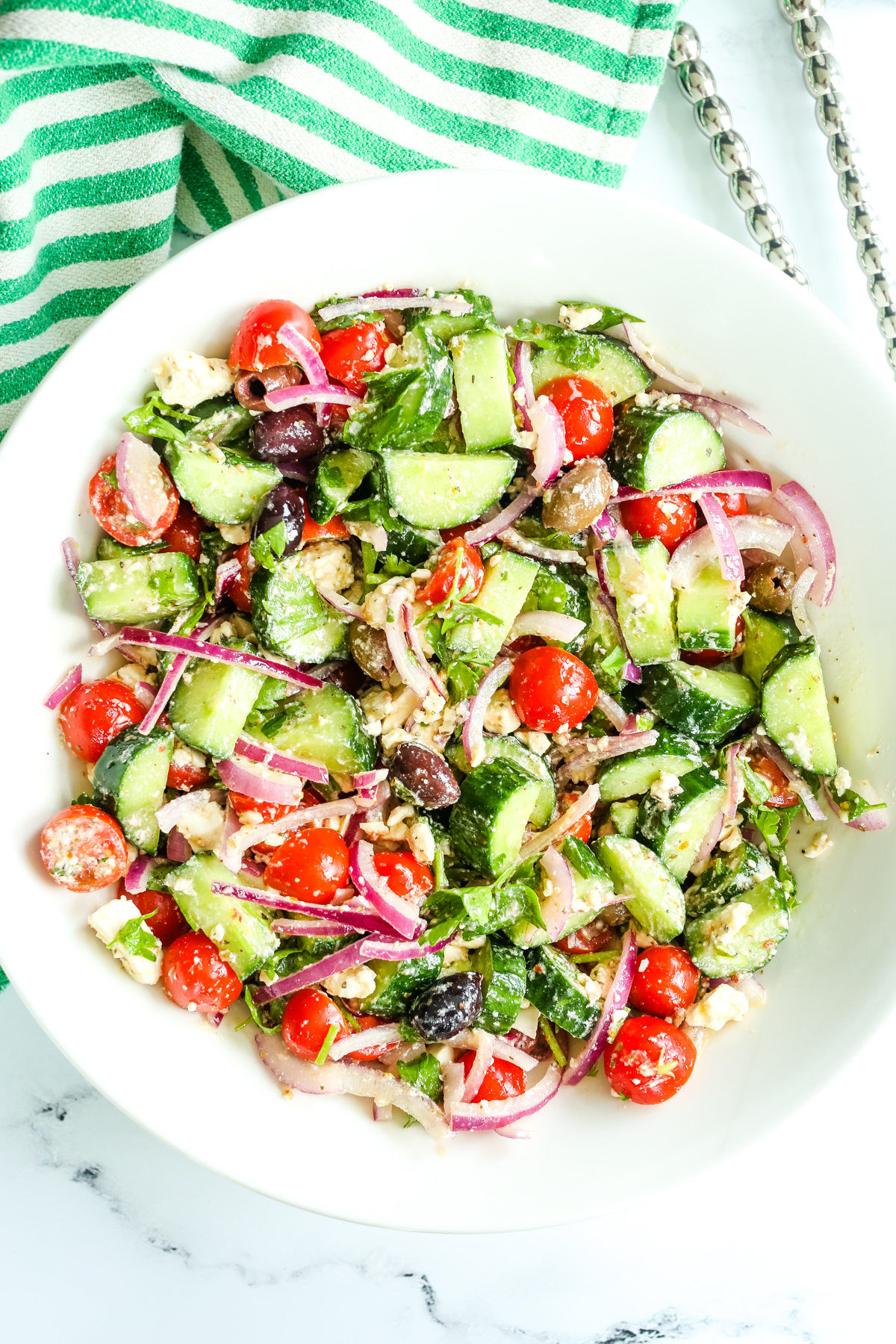 a salad in a bowl with green and white striped napkin