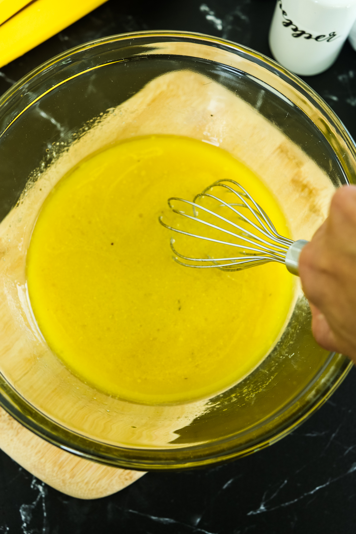 whisking a yellow liquid in a glass bowl