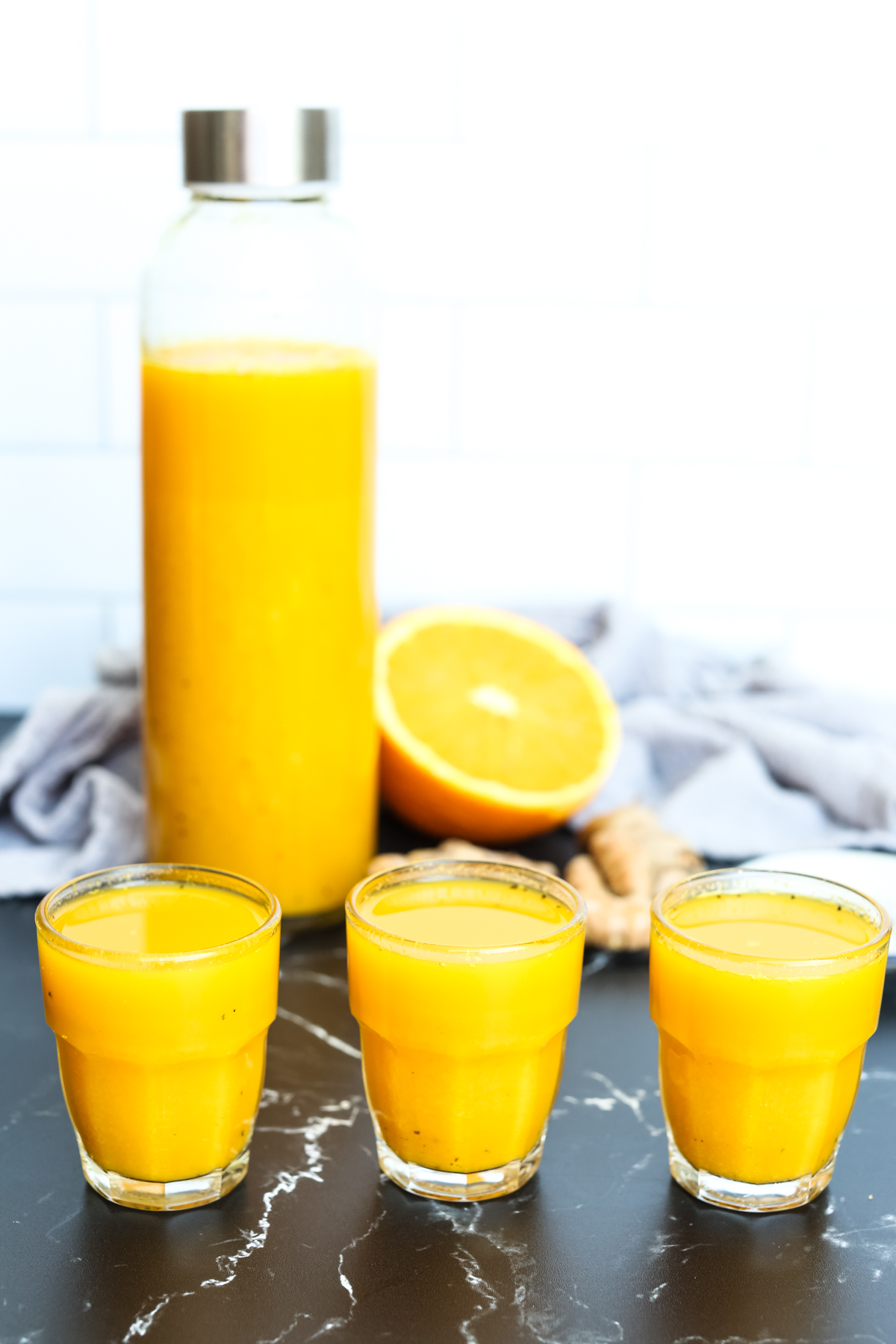 3 turmeric shots lined up with a bottle behind them
