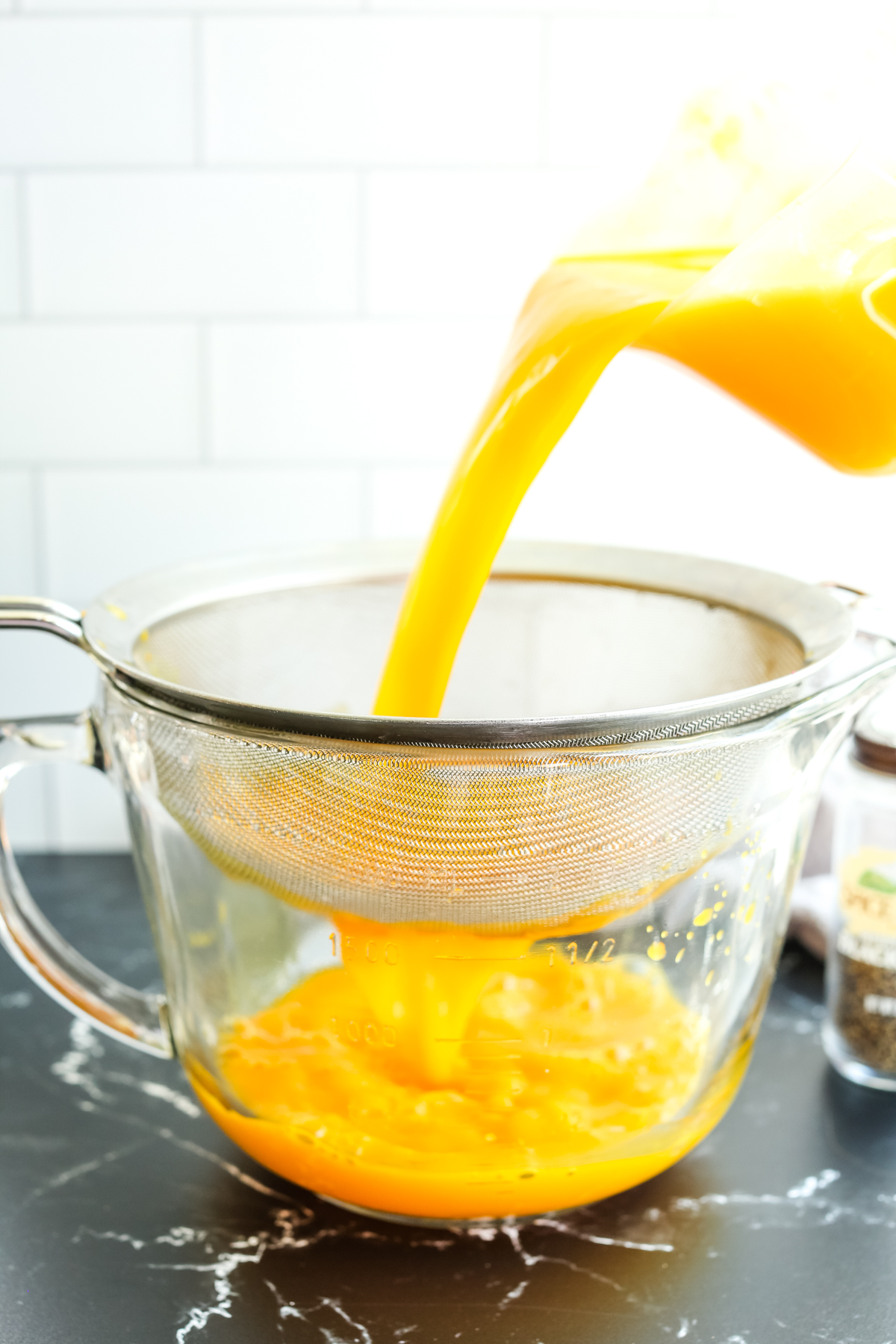 straining orange liquid through a fine mesh sieve