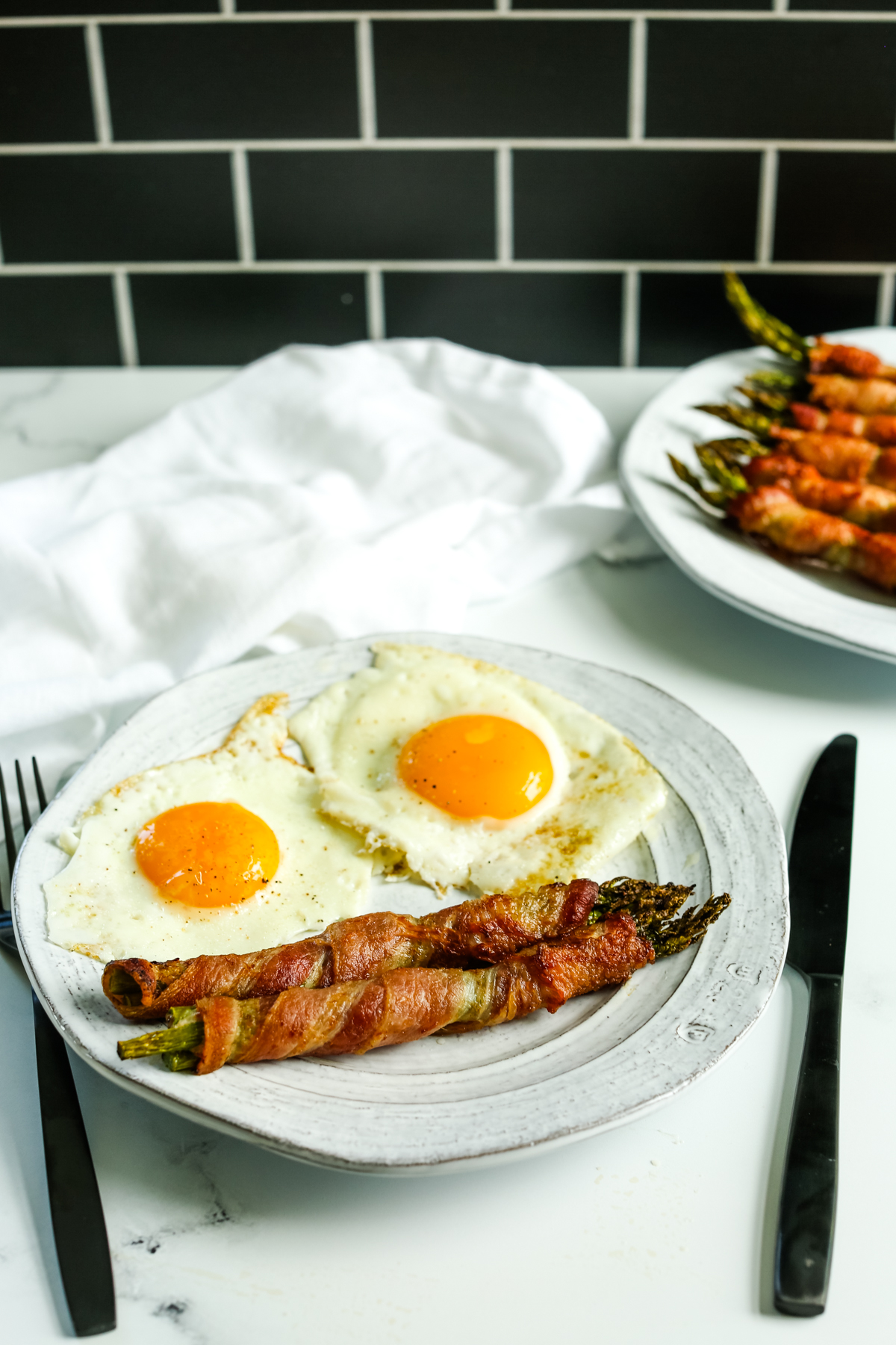 bacon wrapped asparagus on a plate with 2 fried eggs sunny side up