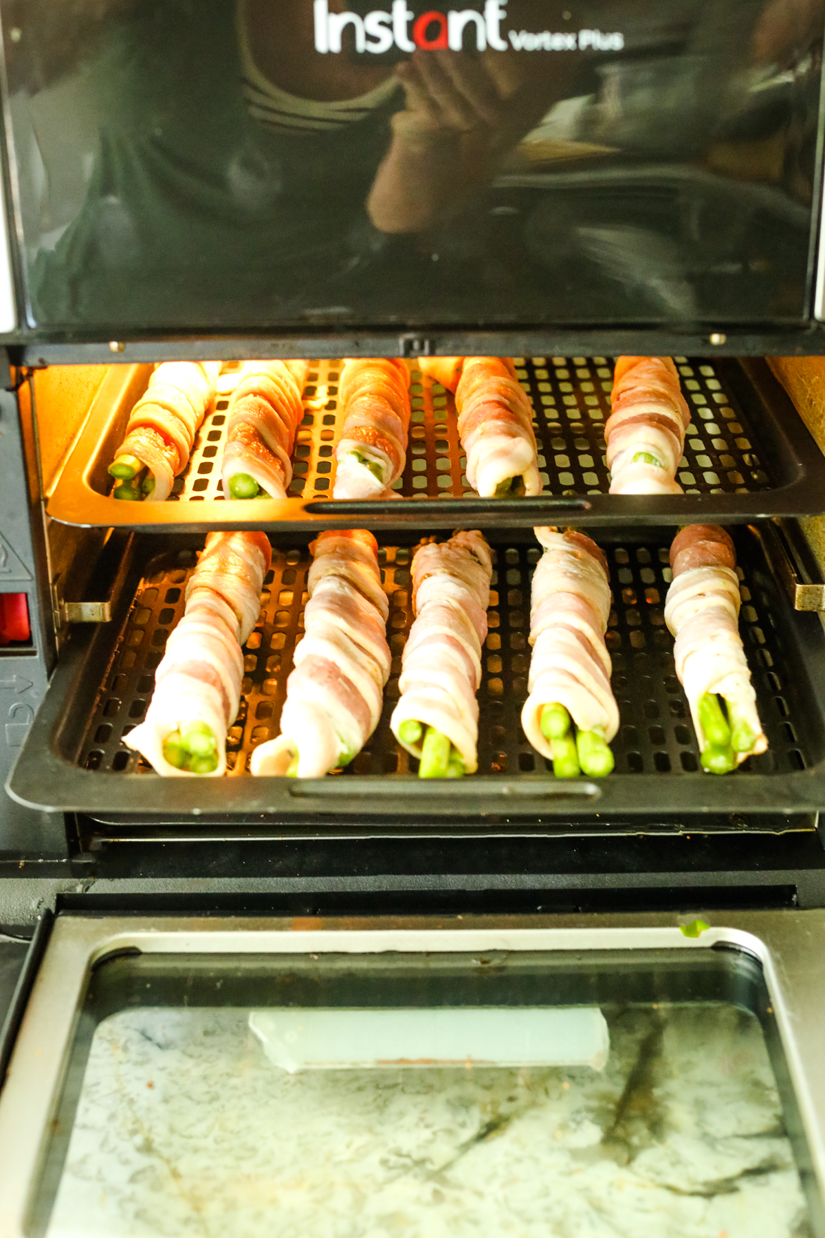 bacon wrapped asparagus on trays in an air fryer