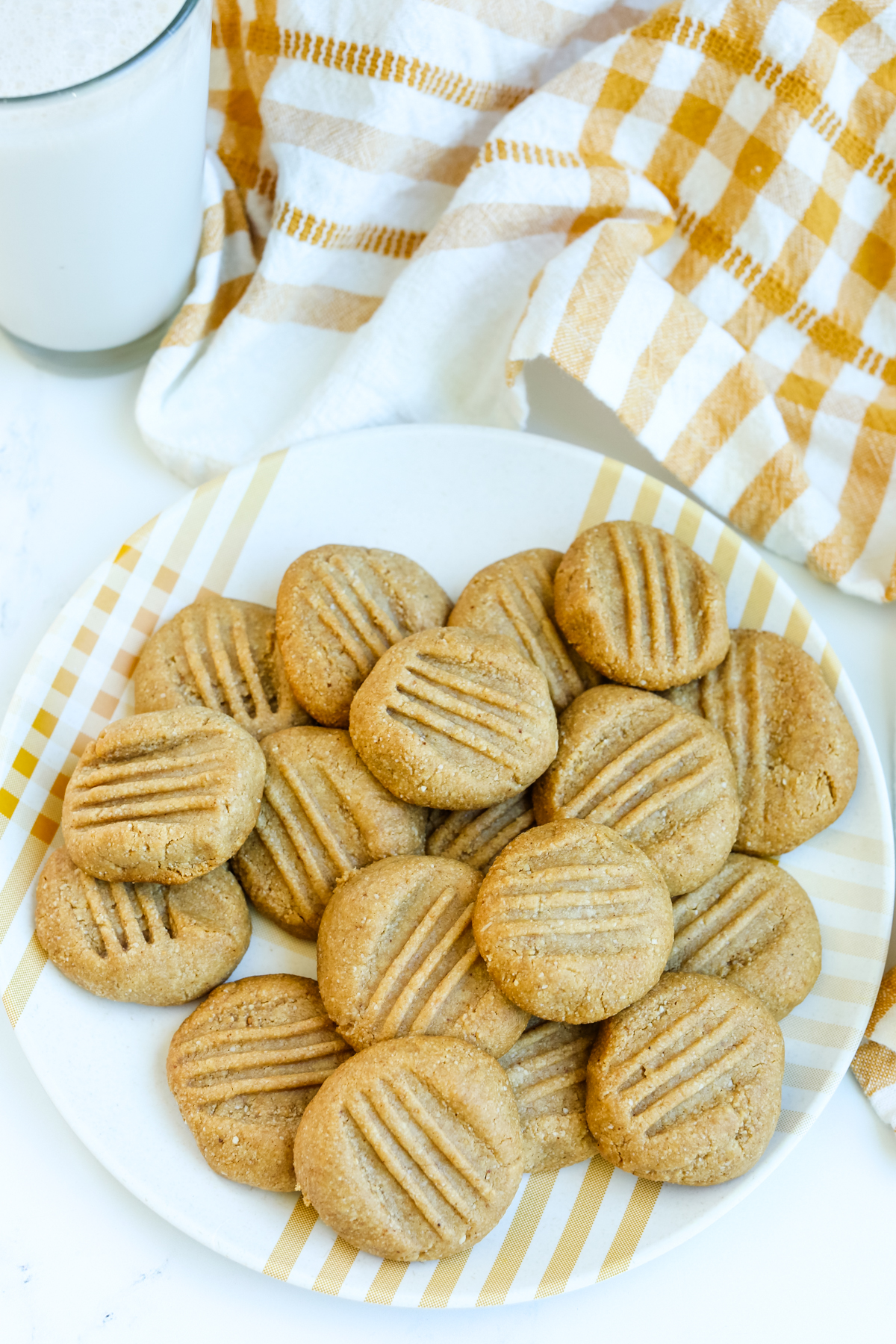 Almond flour peanut butter cookies in a pile on a plate with a glass of milk in the background